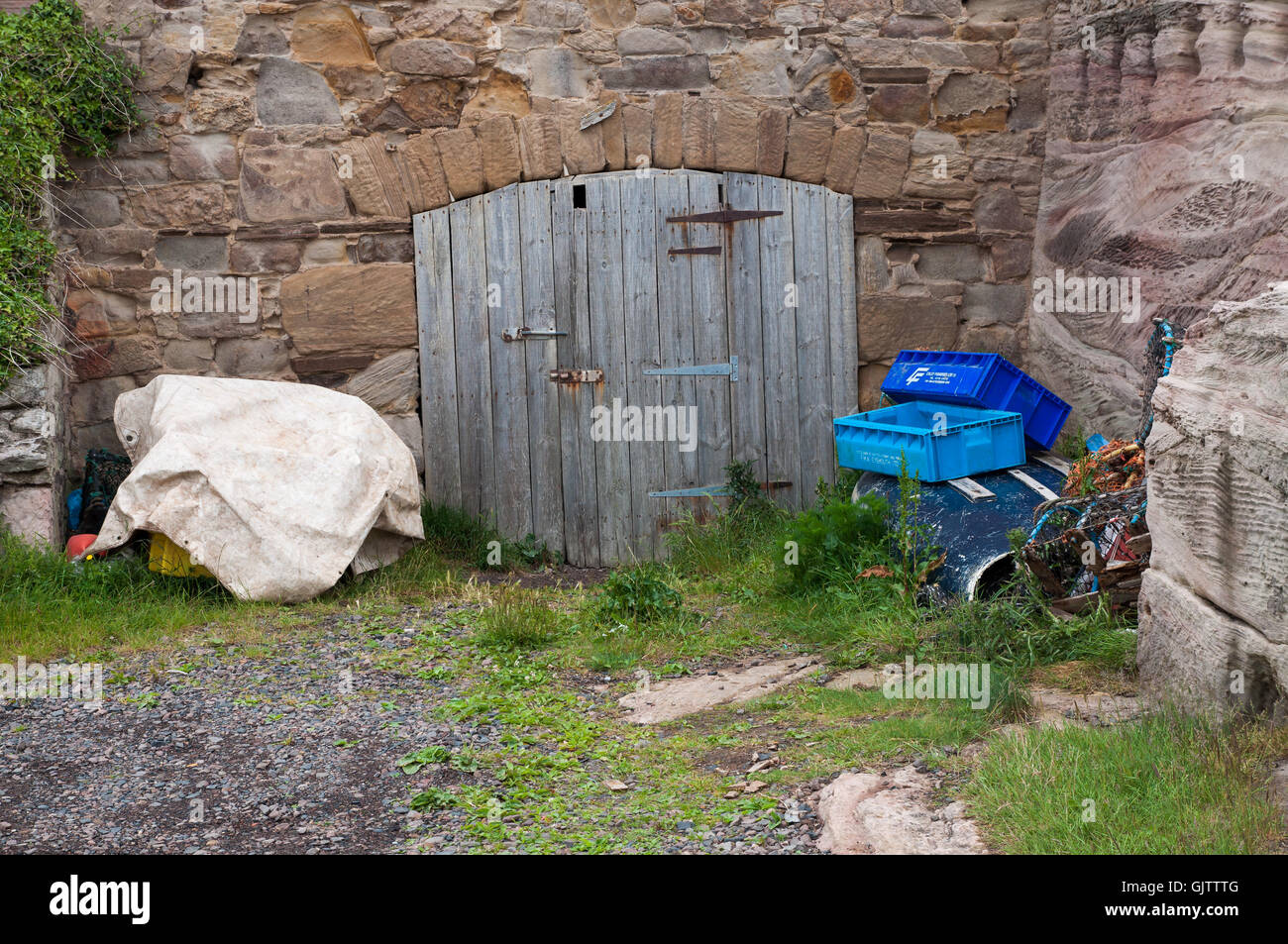 An Old Locked Garage Door In An Old Stone Wall With Debris And