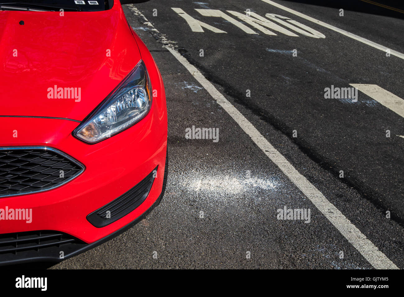 A partial view of a new red car parked in the street. Stock Photo