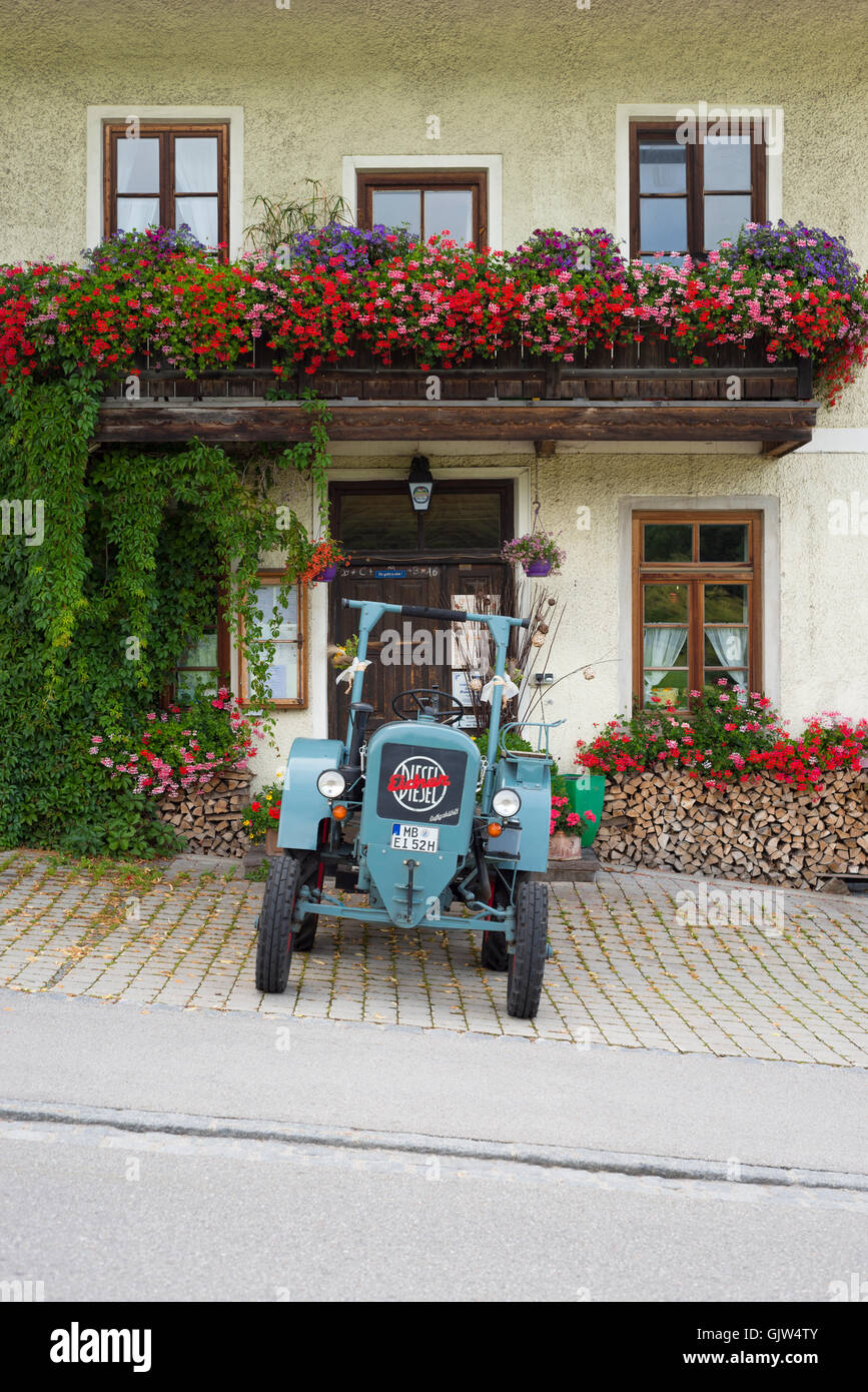 Eicher Diesel vintage tractor parked in front of the Lindl inn covered with blooming geraniums, Bavaria, Germany Stock Photo
