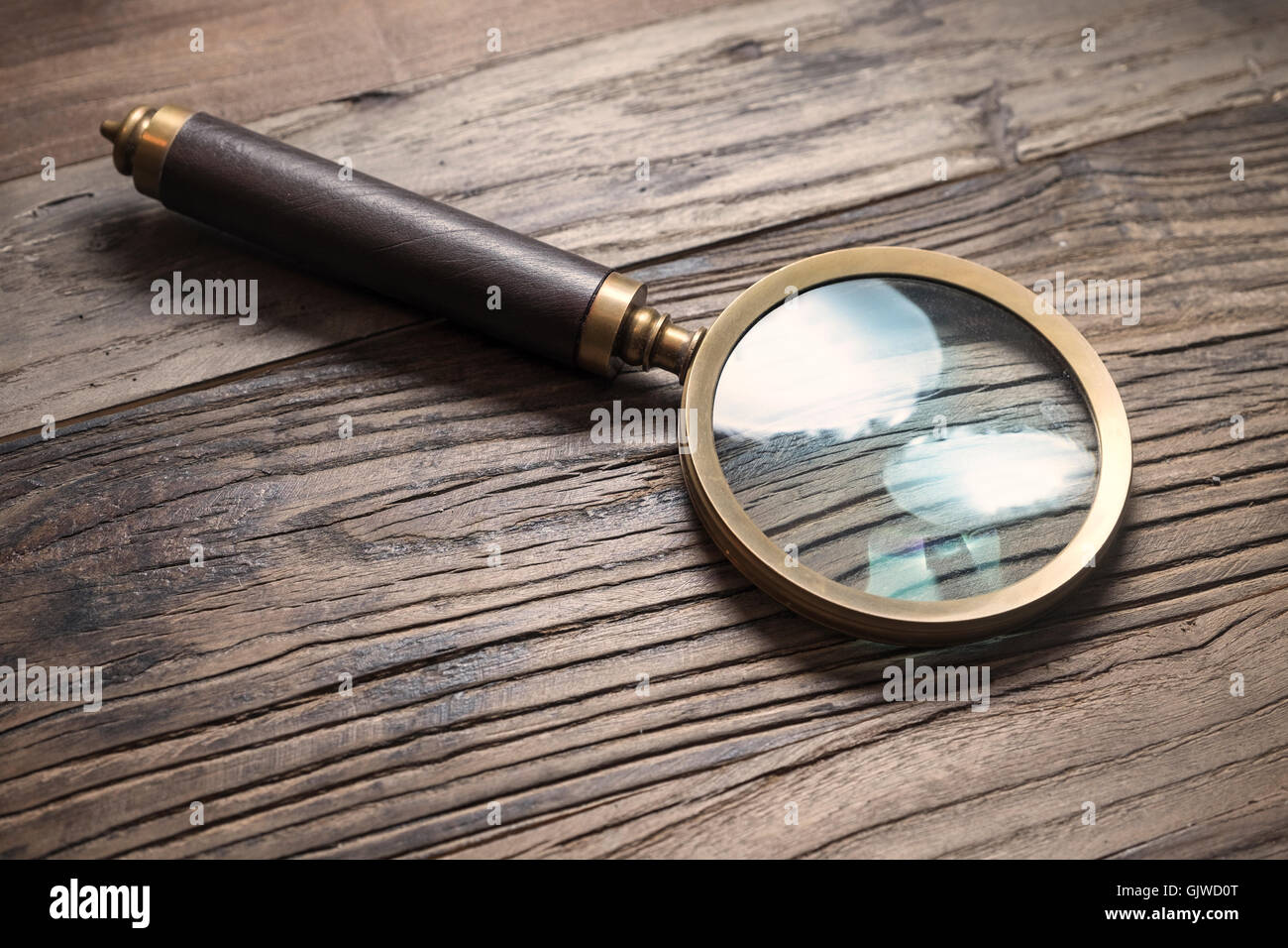 Retro style magnifying glass on a wooden tabe Stock Photo