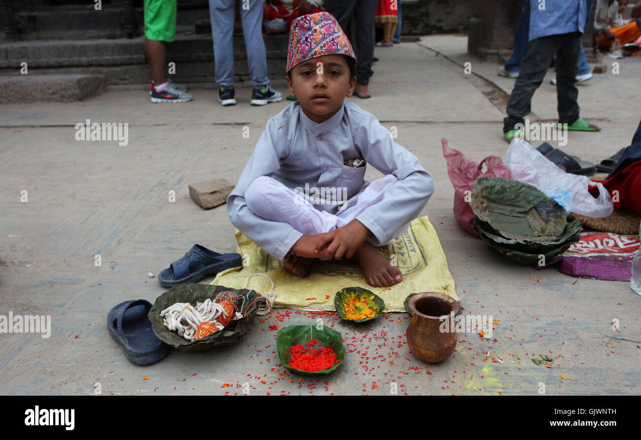 Kathmandu, Nepal. 18th Aug, 2016. A young Hindu Brahmin priest waits for devotees to tie sacred thread during the Janai Purnima Festival in Kathmandu, Nepal, Aug. 18, 2016. Janai Purnima, also known as the festival of threads, is one of the most religiously significant celebrations of Nepal. During the festival, people have the 'Rakshya Bandhan' thread tied around the wrist. The yellow thread is purified by the chanting of Mantras by Brahmins as a symbol of protection from fear and disease. Credit:  Sunil Sharma/Xinhua/Alamy Live News Stock Photo