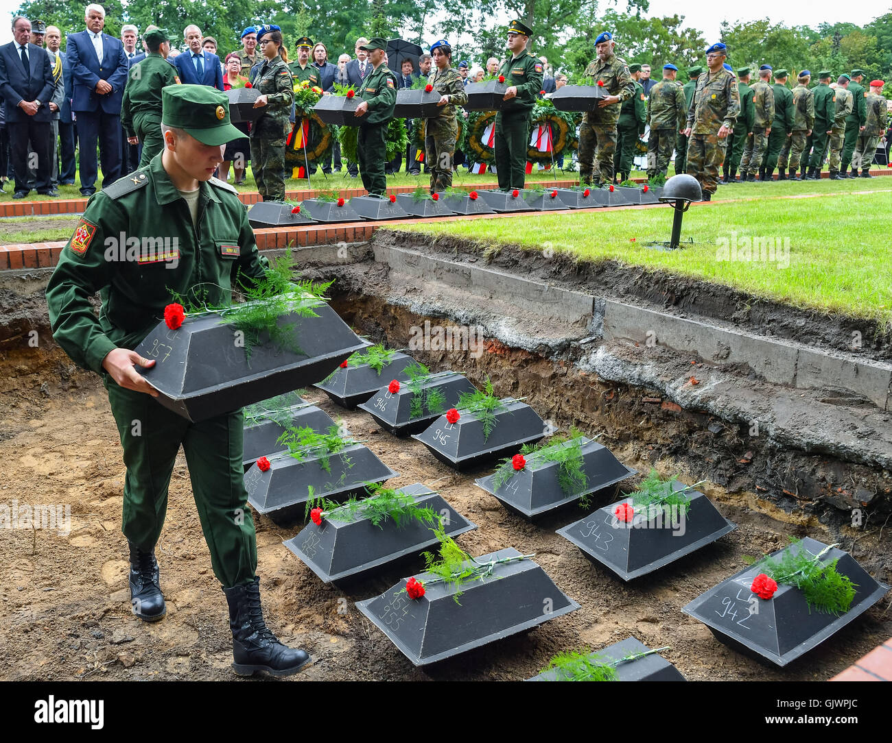 Lebus, Germany. 18th Aug, 2016. A Russian soldier places small coffins containing the remains of Soviet soldiers from the second world war into a grave, during their burial at the military cemetary in Lebus, Germany, 18 August 2016. The 35 red army soldiers died in the heavy fighting in the Oderbruch area in early 1945. The mortal remains were recovered by the German War Graves Commission last year, and can now finally be laid to rest, more than 70 years after the war's end. PHOTO: PATRICK PLEUL/DPA/Alamy Live News Stock Photo