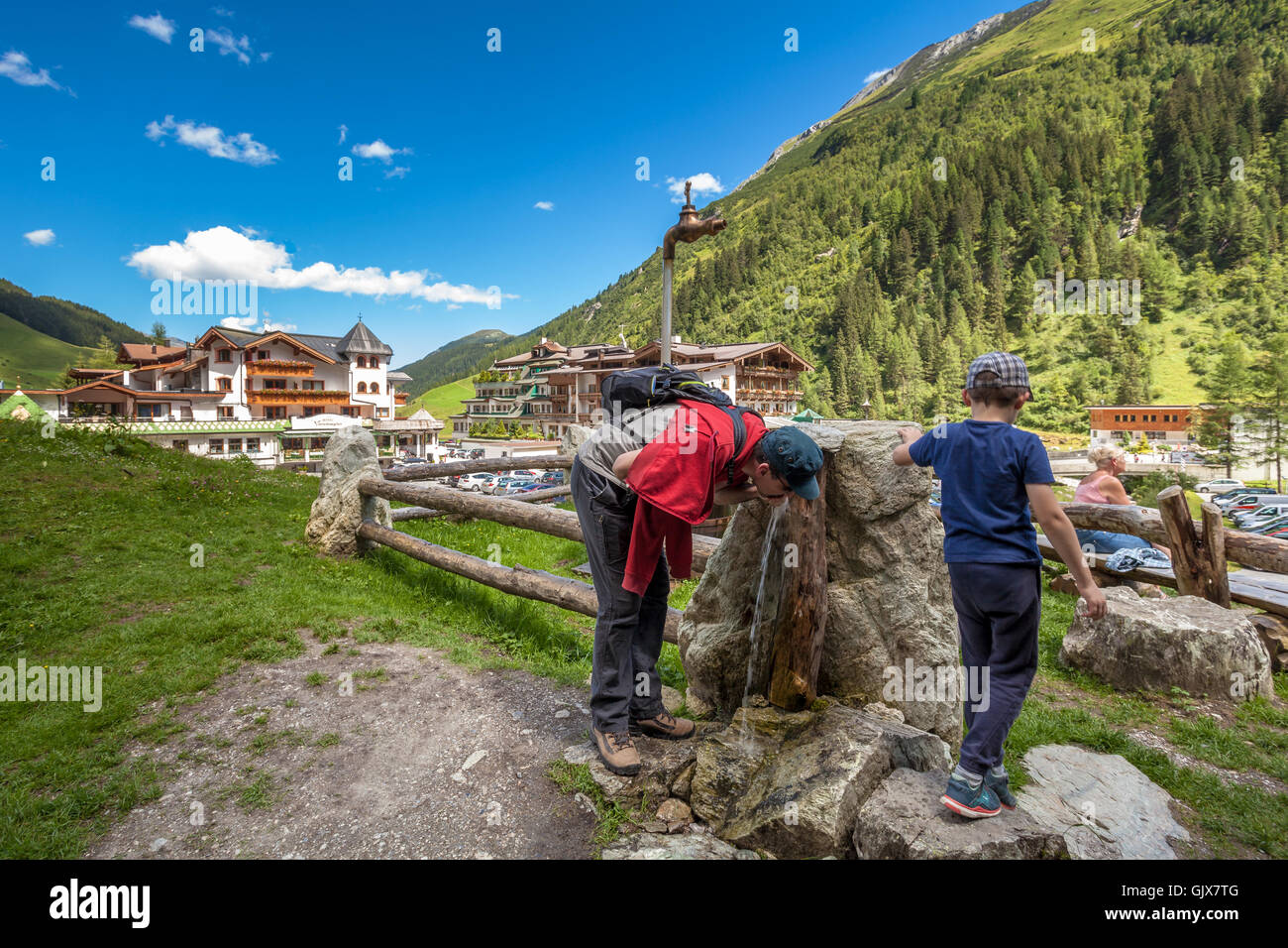 Adult man and son drinking water from natural spring at Hintertux Austria Stock Photo