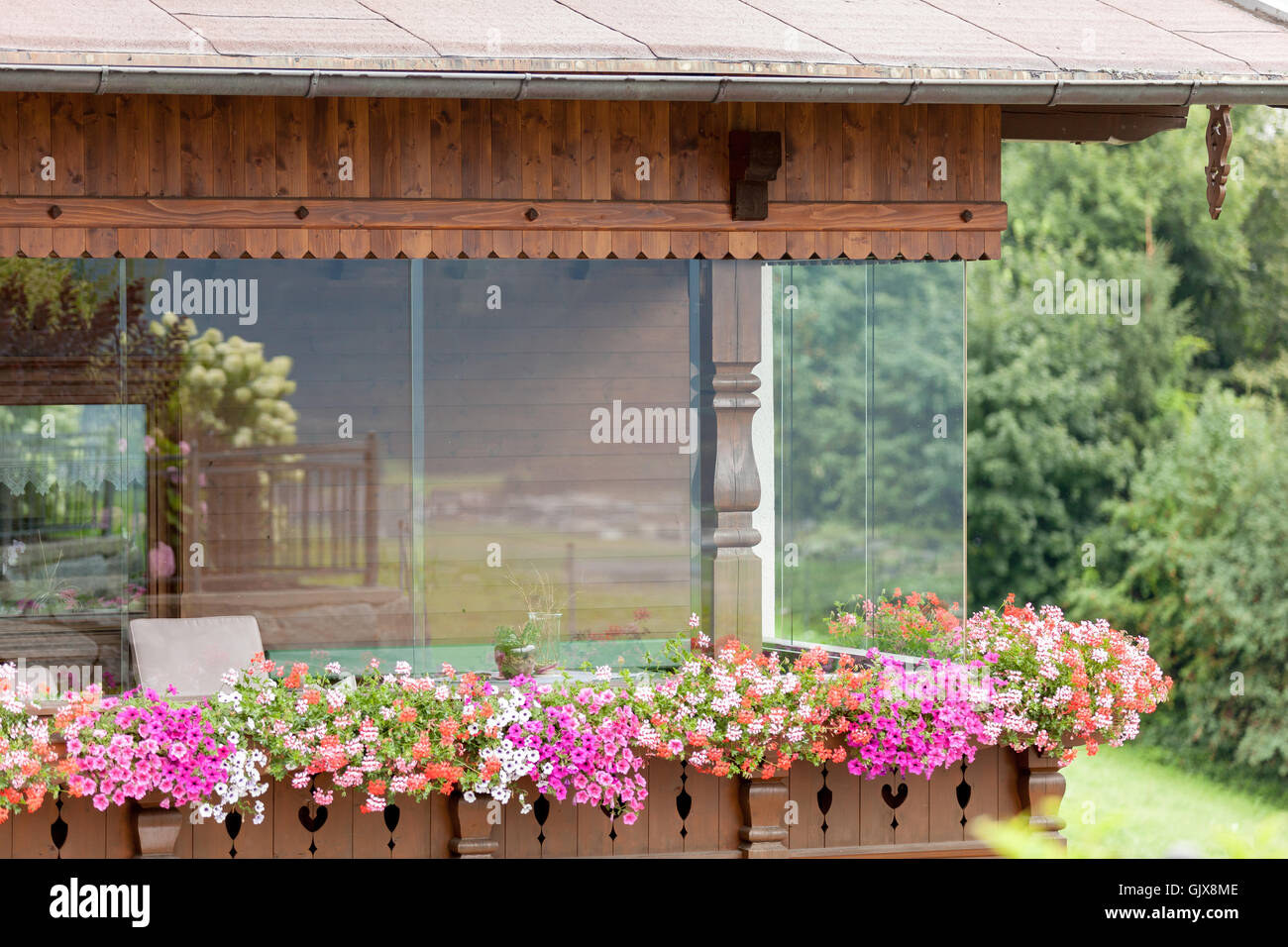 wooden house in Austria with big windows and flowers on the balcony Stock Photo