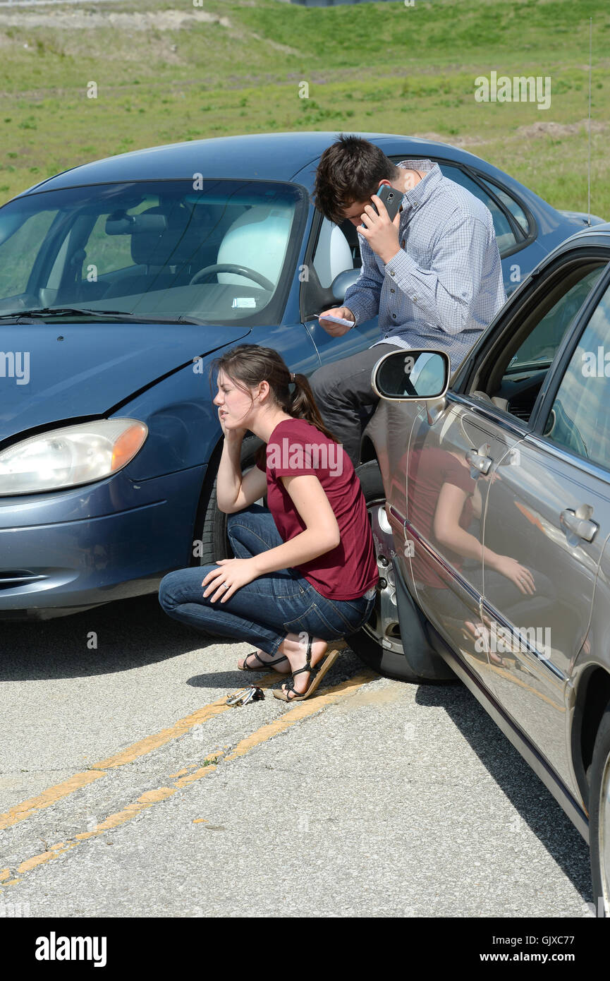 Young woman and man using cellphones after car accident Stock Photo