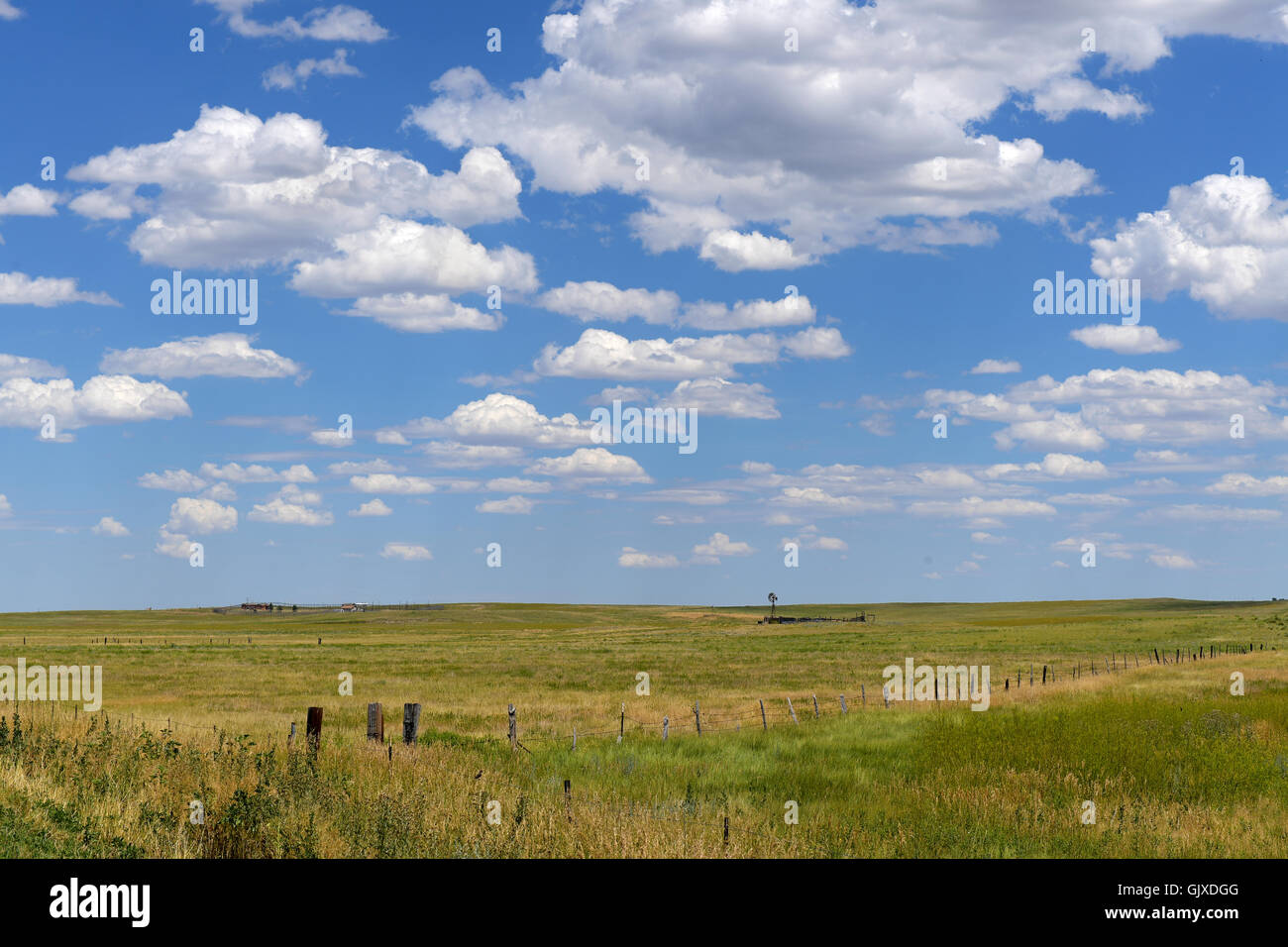 Cloudscape with prairie and wind turbine in distance Stock Photo