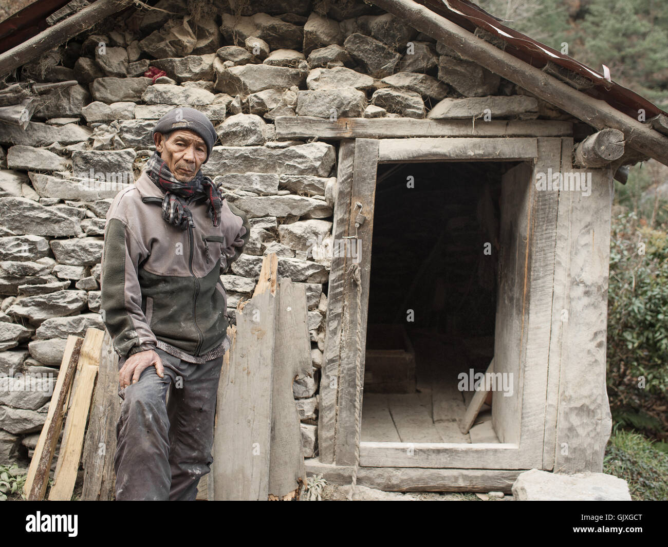 A Nepalese man stands outside a stone mountain barley mill near Phakding Stock Photo