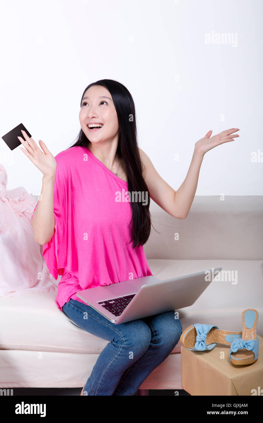 Studio shot Young woman sitting on the couch using laptop Stock Photo ...