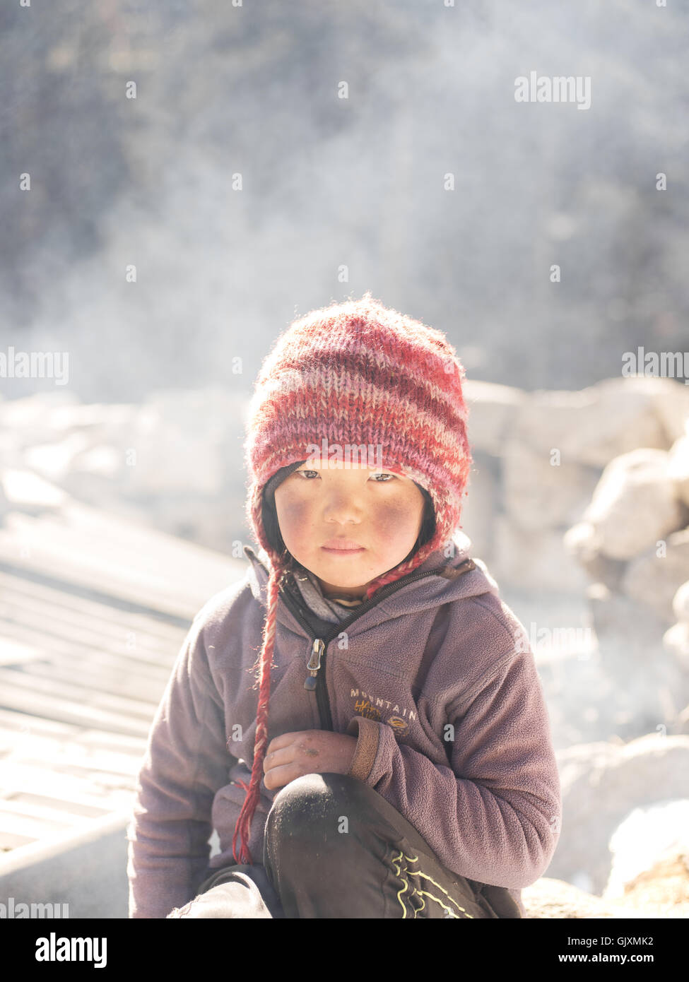 A young Nepalese girl sits in the cold winter near Namche Stock Photo