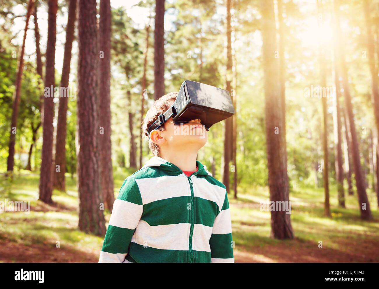 Child standing in the forest in virtual reality glasses Stock Photo
