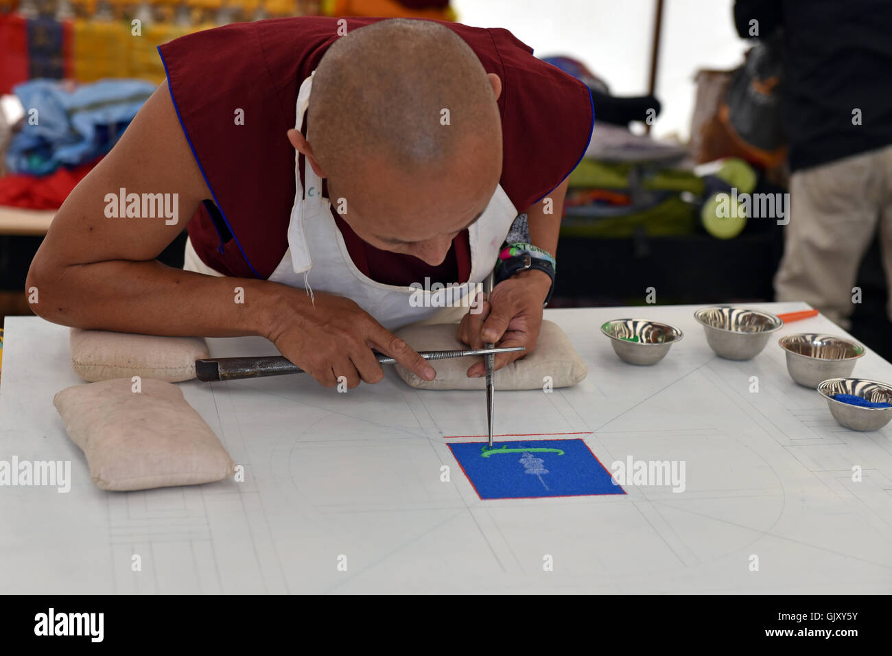 A Tibetan Monk works on a sand mandala as part of his meditation Stock Photo
