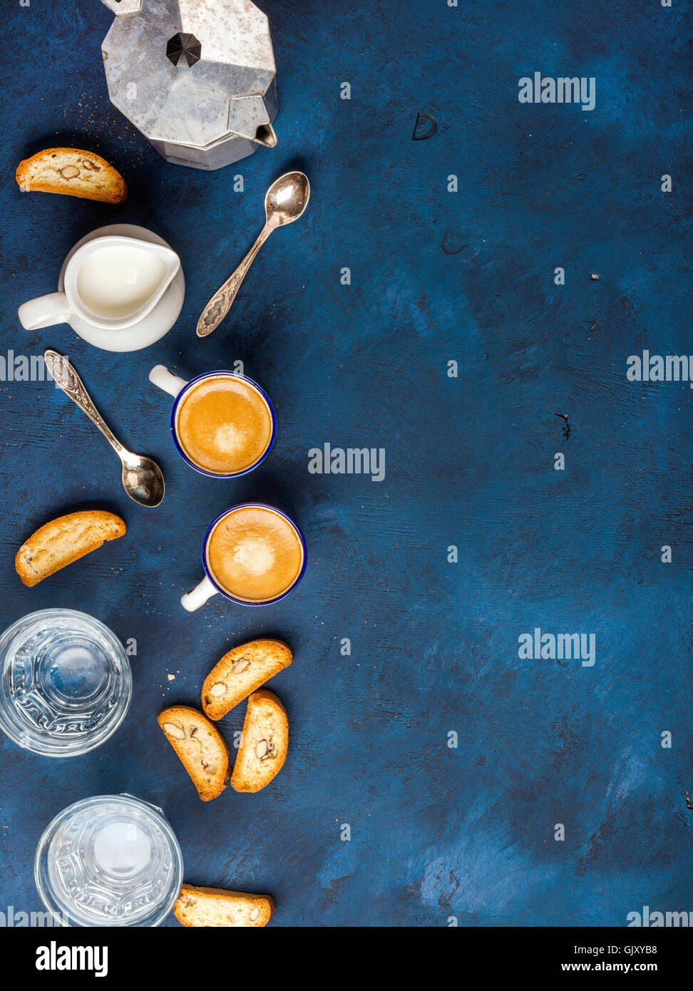 Coffee espresso in cups with italian cantucci, cookies and milk in jug over dark blue painted plywood background, top view, copy Stock Photo