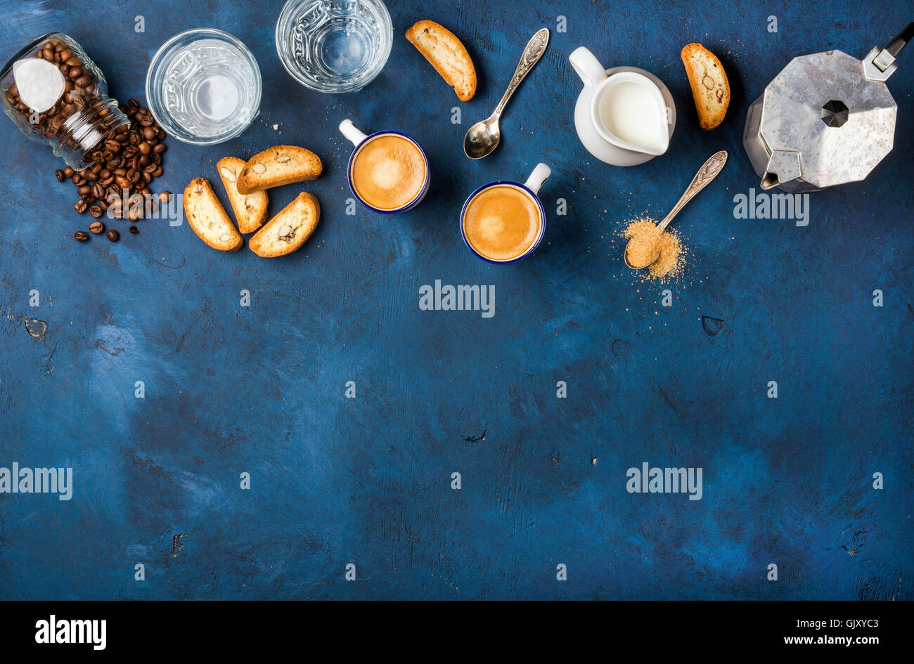 Coffee espresso in cups with italian cantucci, cookies and milk in jug over dark blue painted plywood background, top view, copy Stock Photo