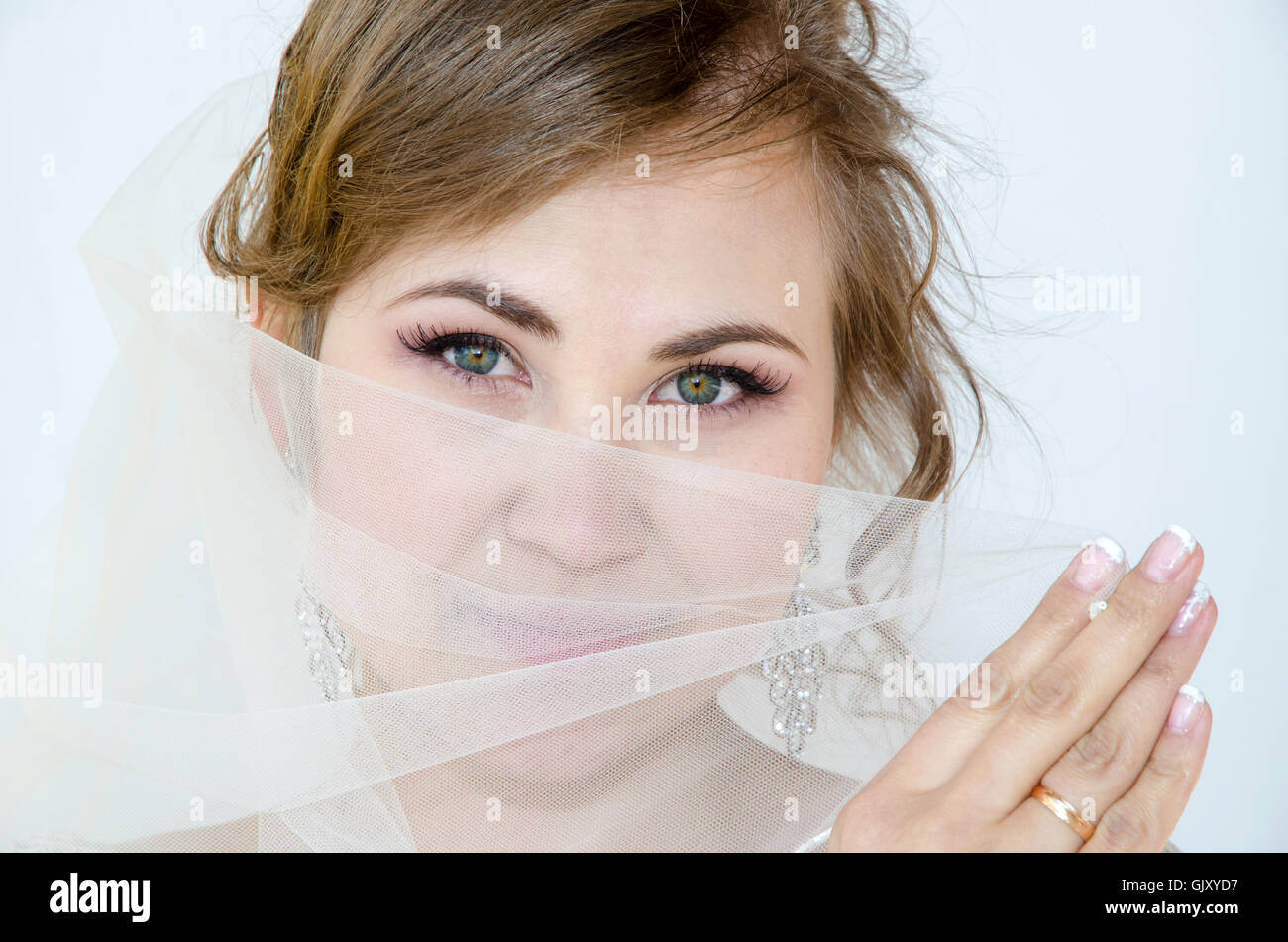Bride with eyes open, holding veil, face Stock Photo