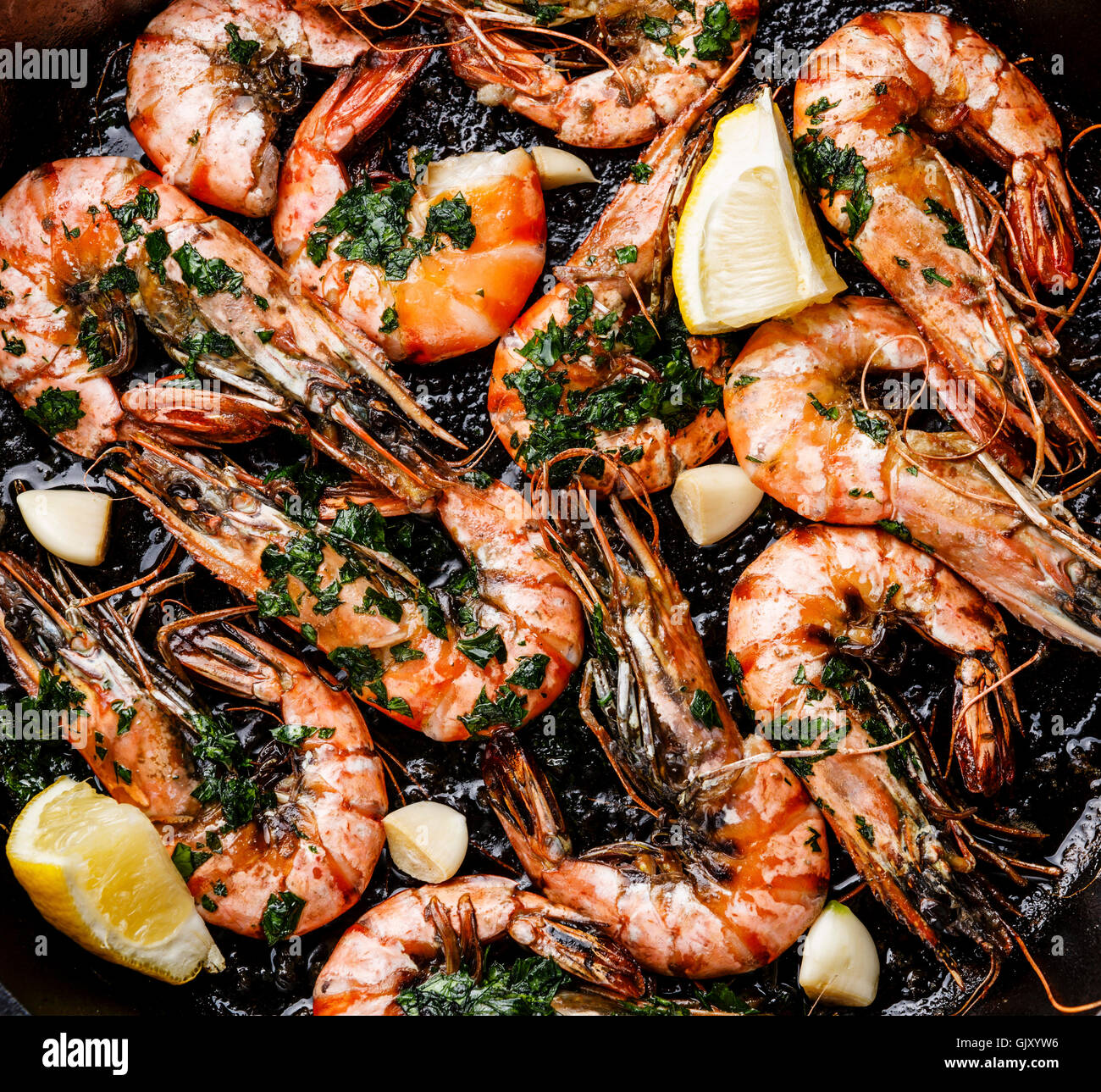 Tiger prawns roasted on frying pan with green sauce close up Stock Photo