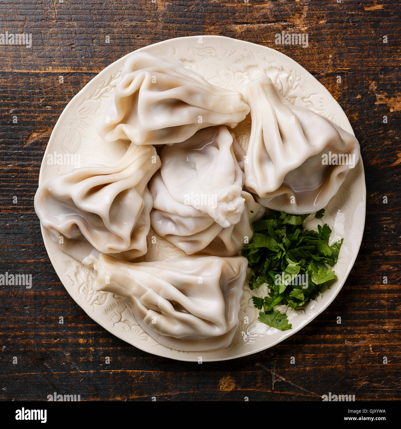 Georgian dumplings Khinkali with meat and greens coriander leaves on white plate Stock Photo