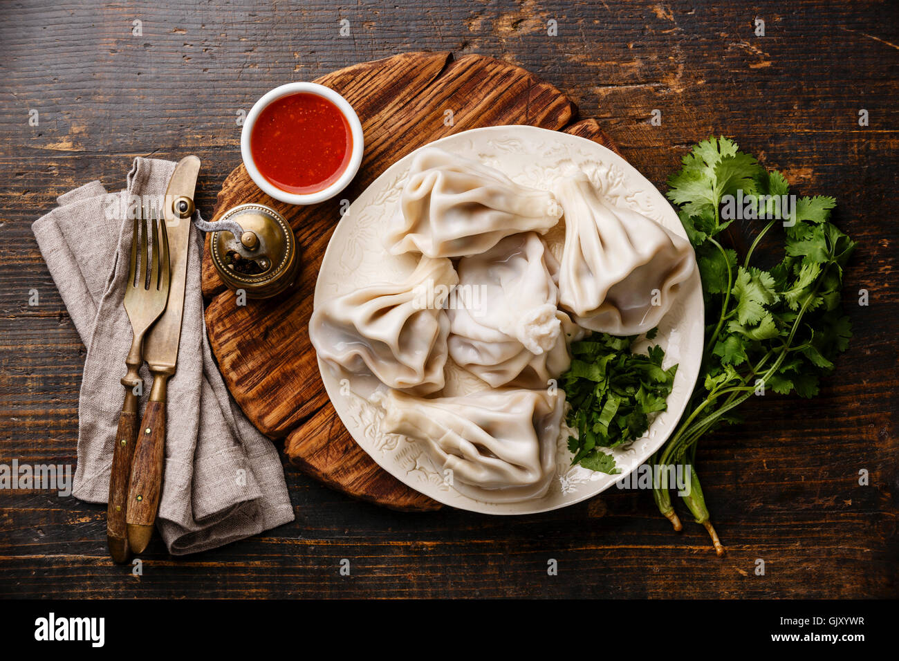 Georgian dumplings Khinkali with meat and tomato spicy sauce satsebeli on wooden background Stock Photo