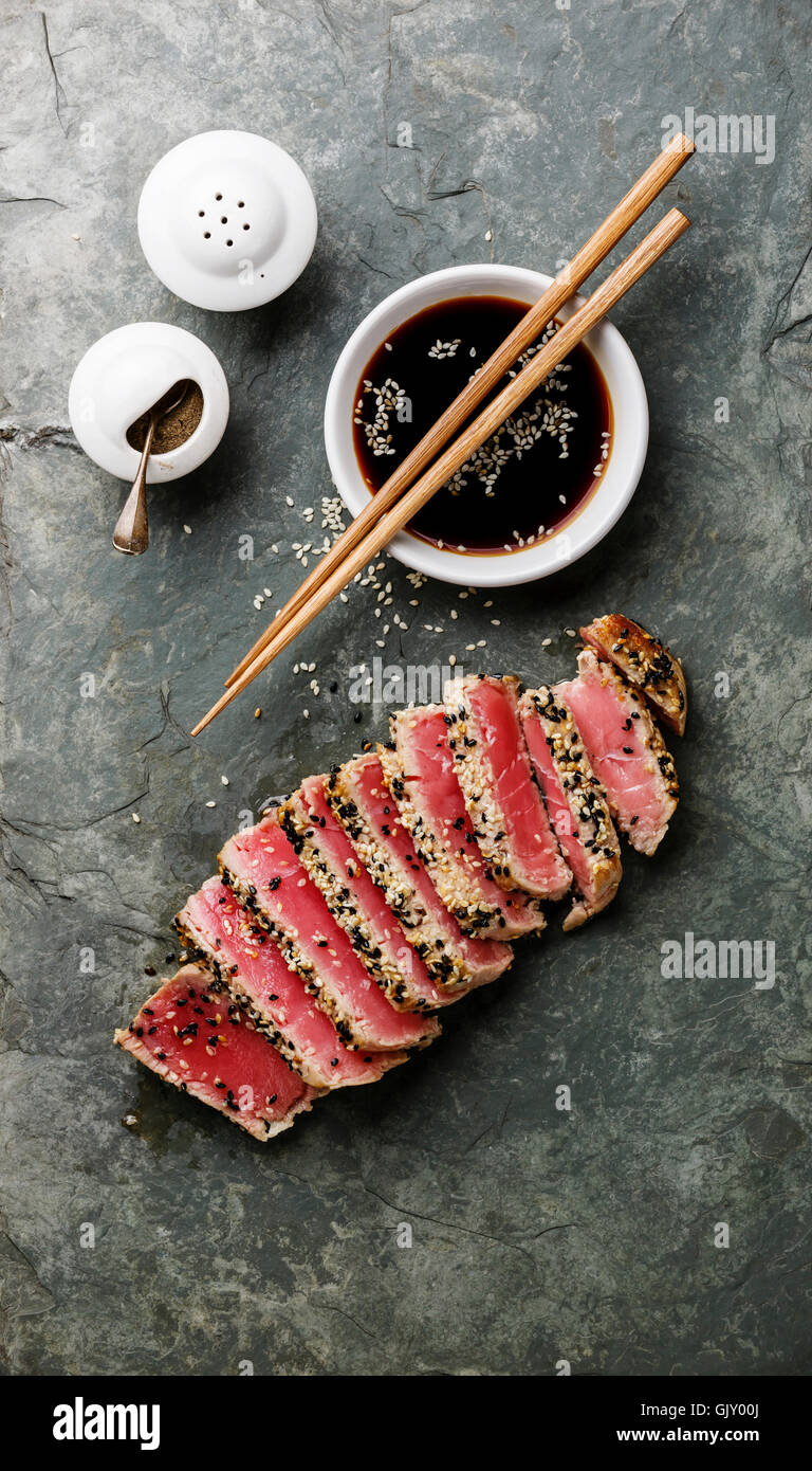 Sliced grilled Tuna steak in sesame and soy sauce on stone slate board Stock Photo