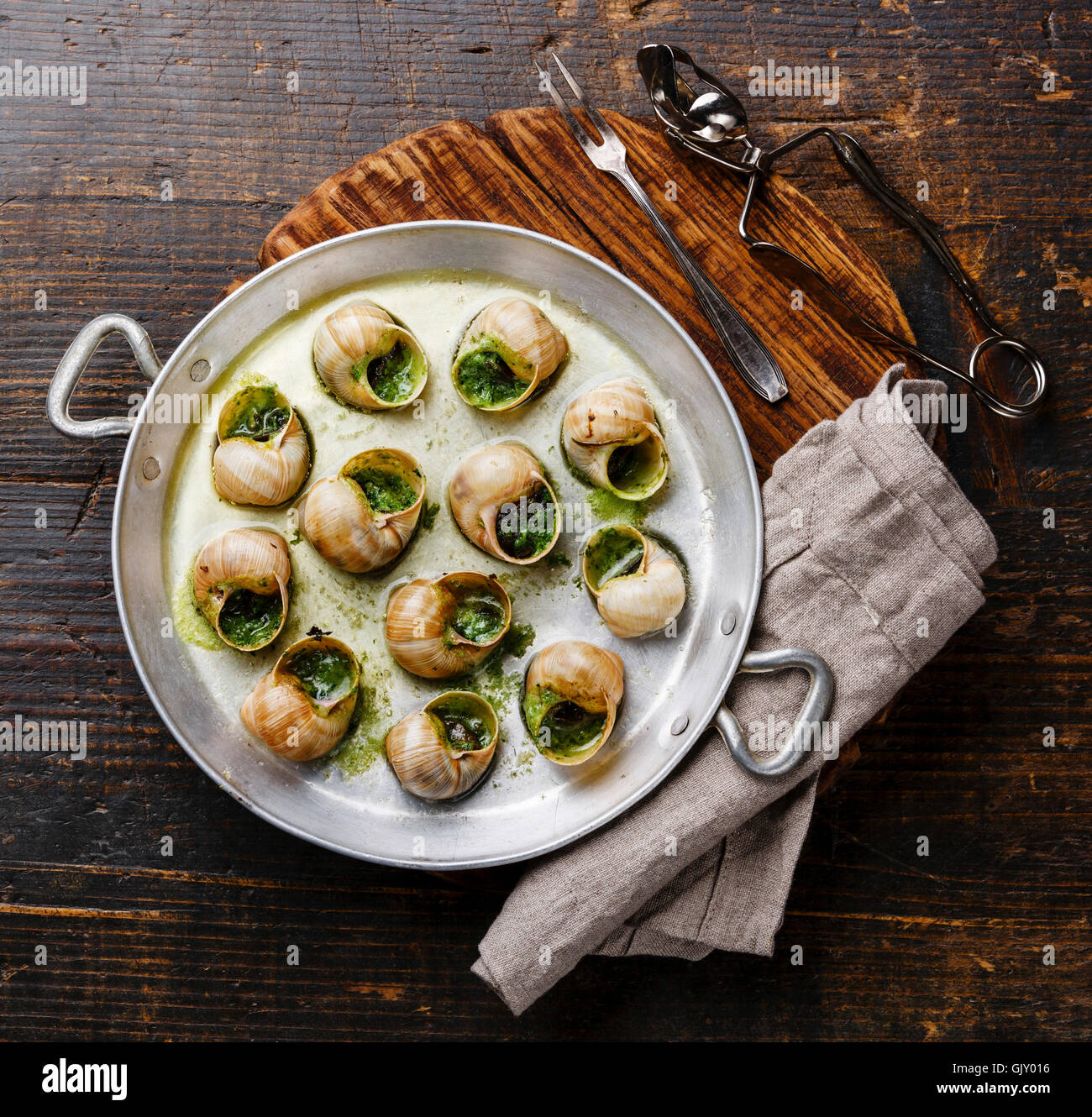 Bourgogne Escargot Snails with garlic herbs butter in aluminum pan on rustic wooden background Stock Photo
