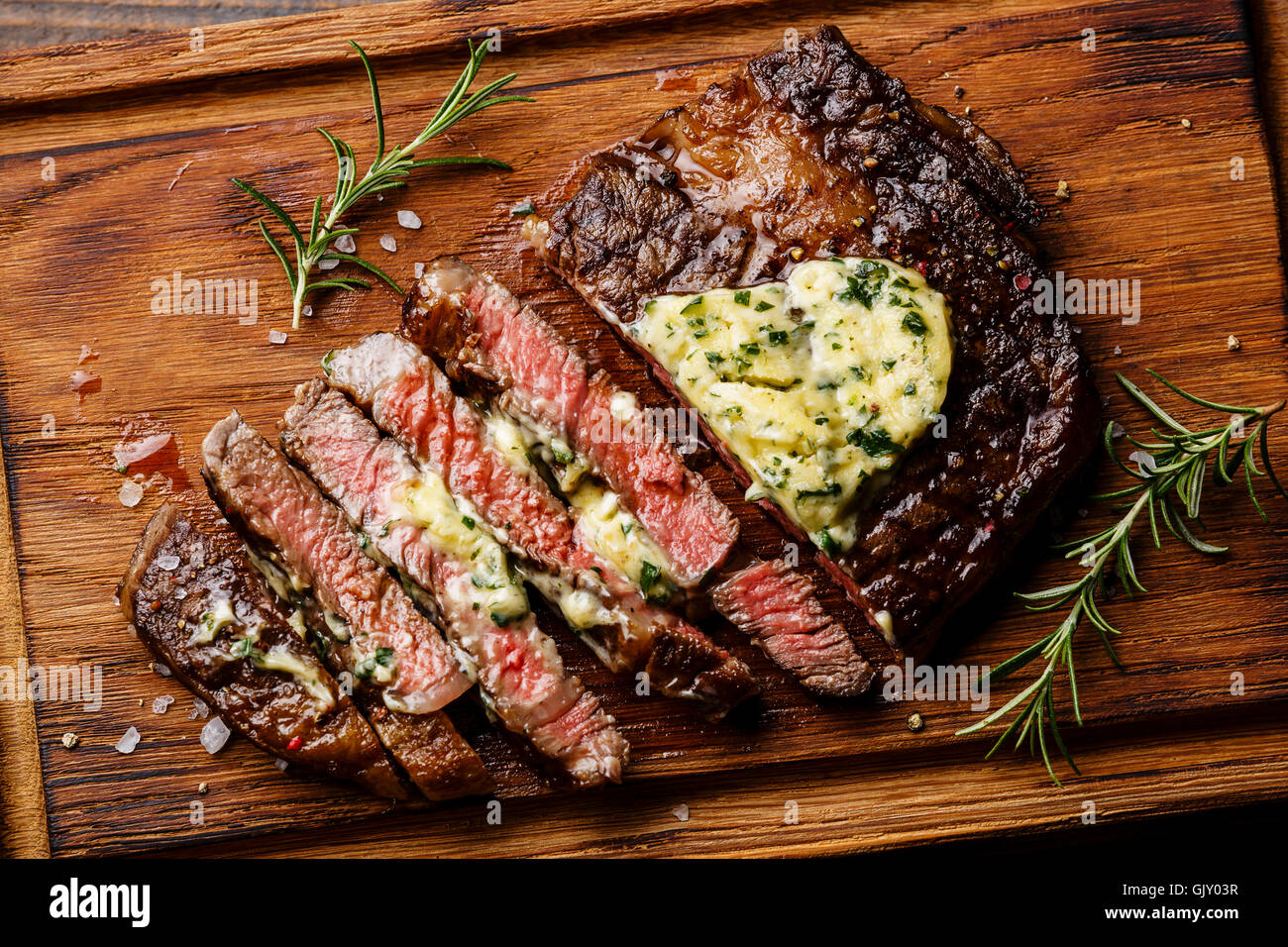 Sliced grilled Medium rare barbecue steak Ribeye with herb butter on cutting board close up Stock Photo
