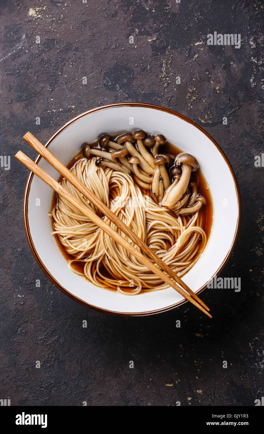 Asian Ramen noodles with shimidzhi mushrooms in broth and chopsticks on dark background Stock Photo