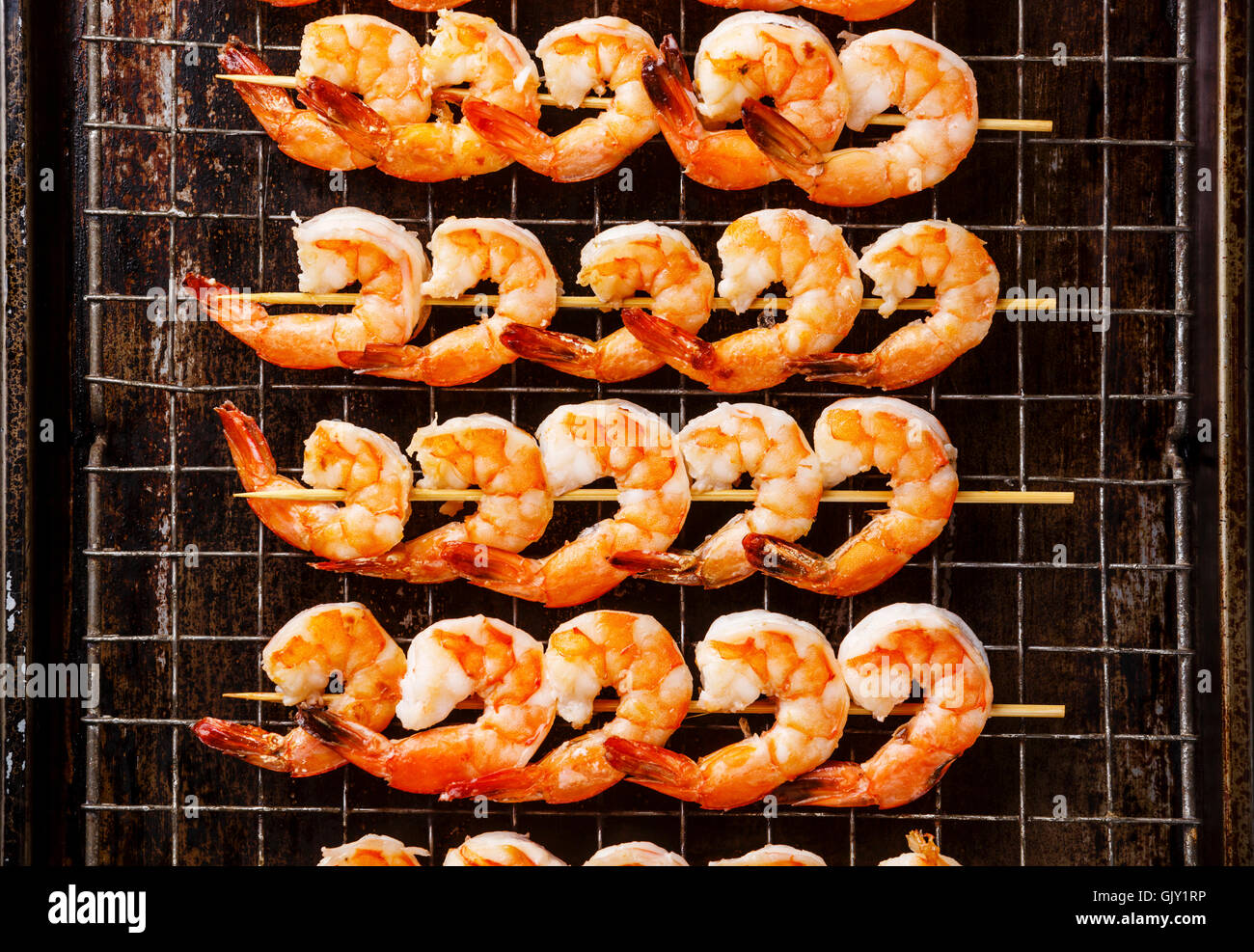 Grilled fried Prawns on skewers on metal grid baking sheet background Stock Photo