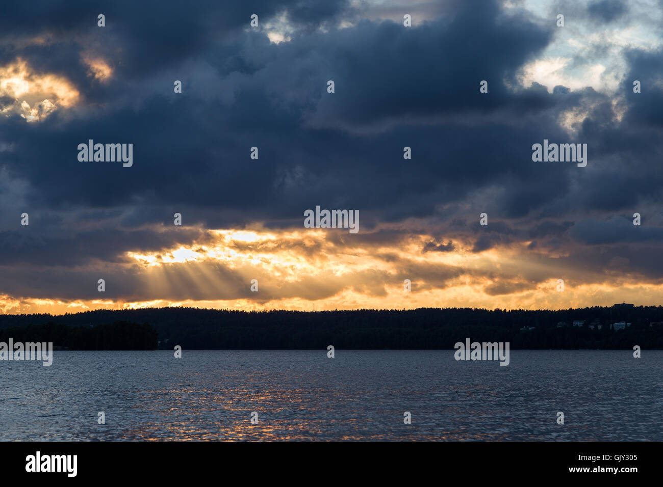 View of dark and dramatic clouds, rays of light and a lake in Finland ...