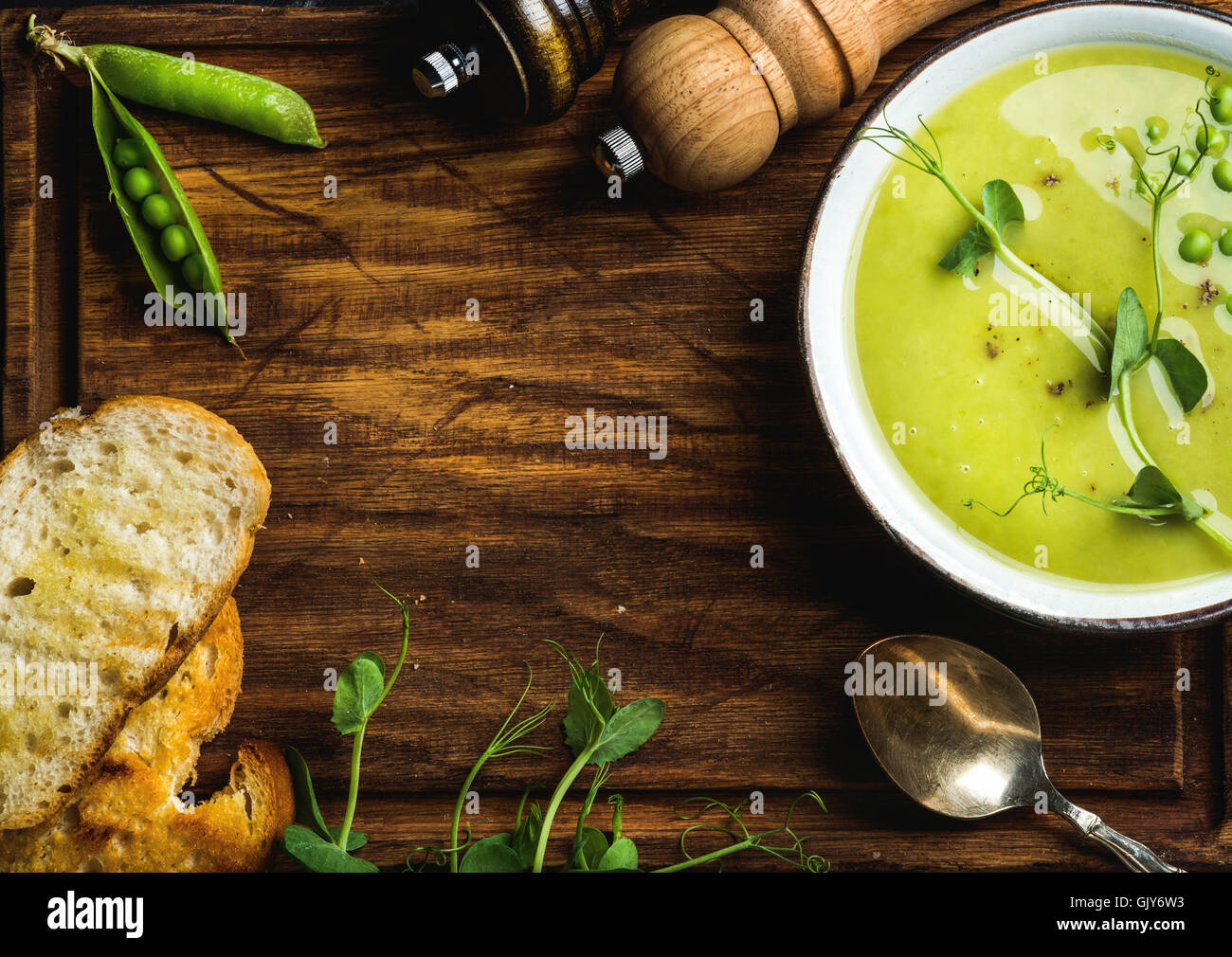 Fresh homemade pease cream soup in white bowl with bread over rustic wooden backdrop, top view, copy space, horizontal compositi Stock Photo