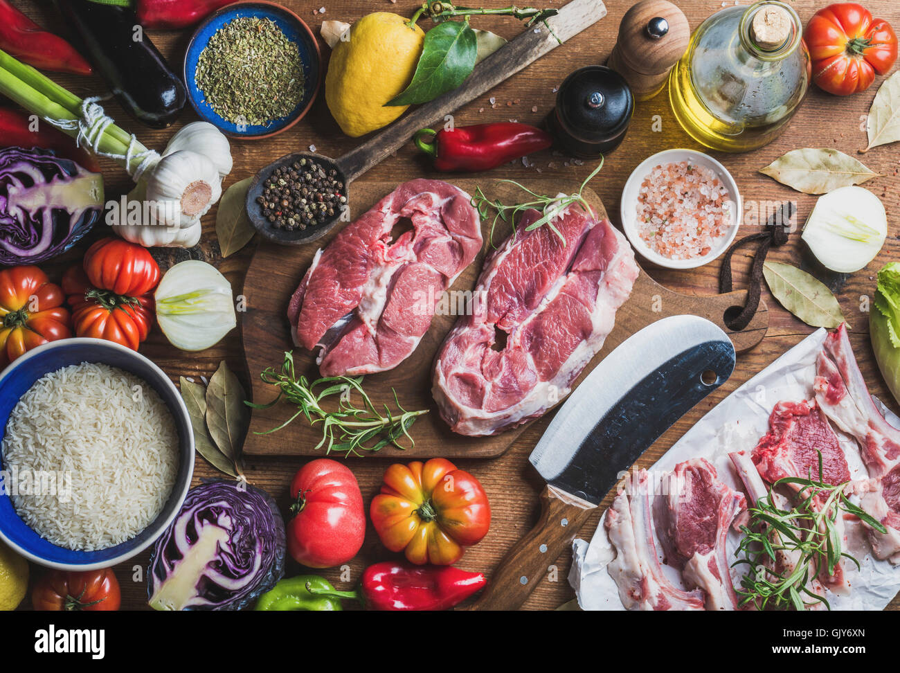 Ingredients for cooking meat dinner. Raw uncooked lamb meat assortment, rice, olive oil, spices and vegetables over wooden backg Stock Photo
