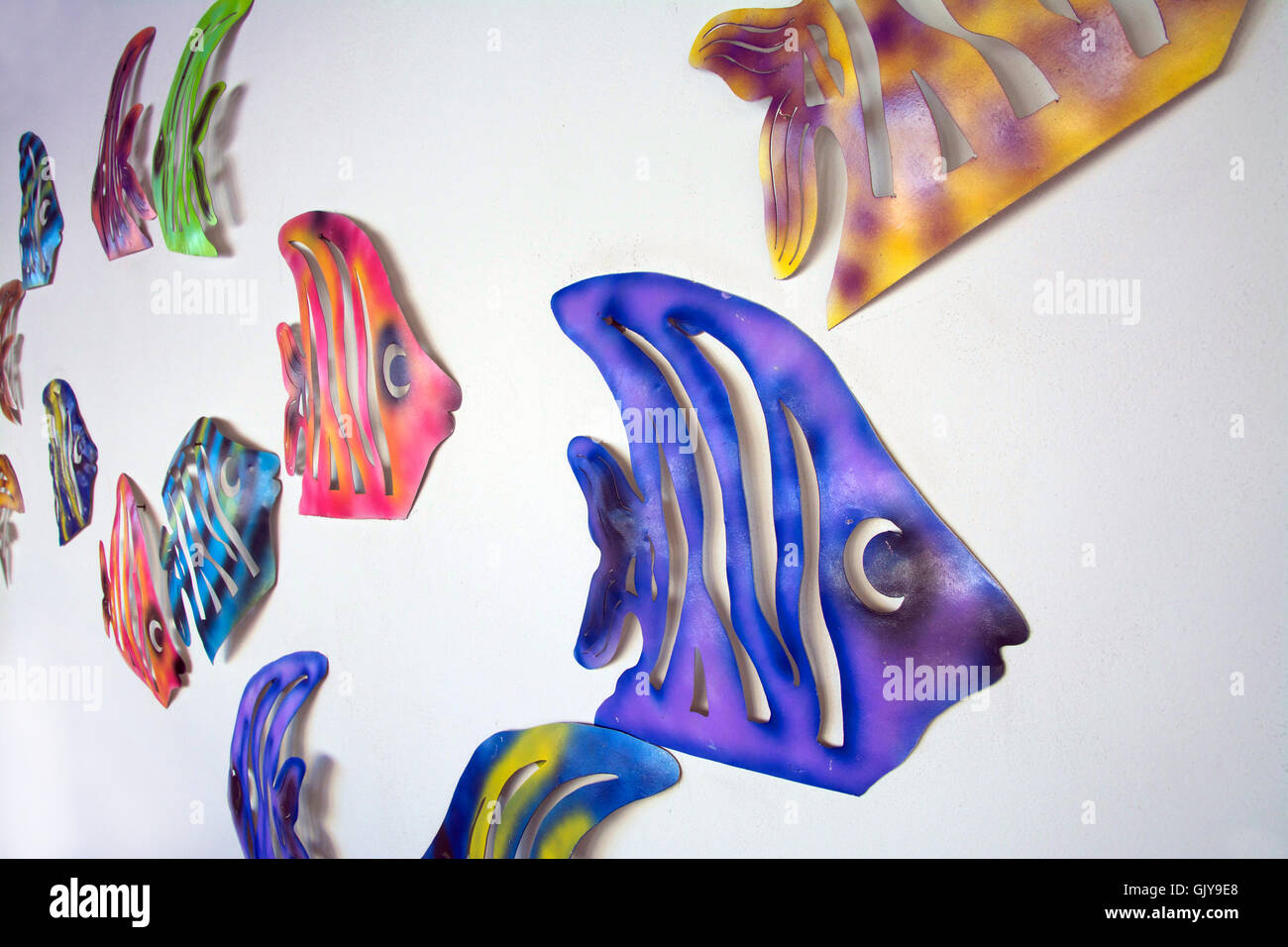 School of Colourful Metal Tropical Fish Cutout Designs Swimming Two Directions Mounted Restaurant Wall San José del Cabo, Mexico Stock Photo