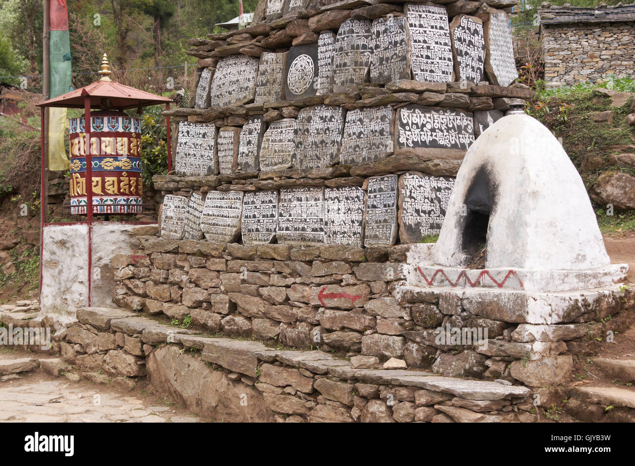 Buddhist Mani stones and prayer wheel along the trekking route to Everest Base camp in Nepal Stock Photo