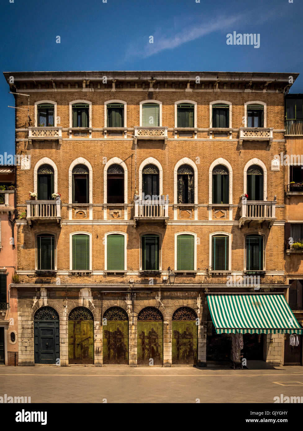 Traditional brick building with venetian blinds at the arched windows. Stock Photo