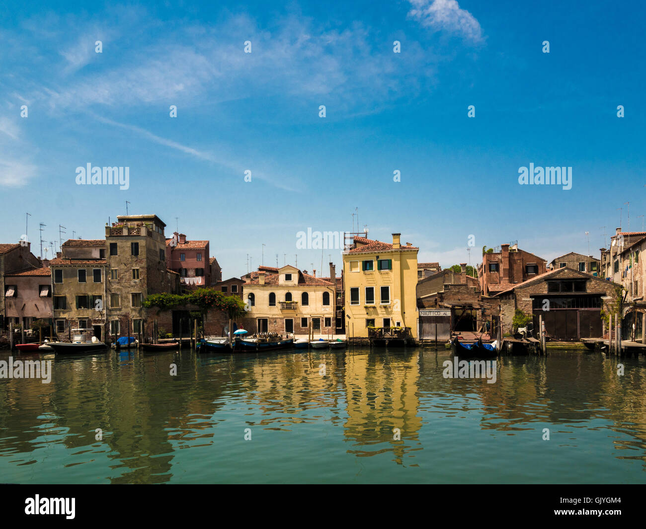 Traditional  buildings, with moored boats and gondolas along the  Canale di San Pietro, Venice. Italy. Stock Photo