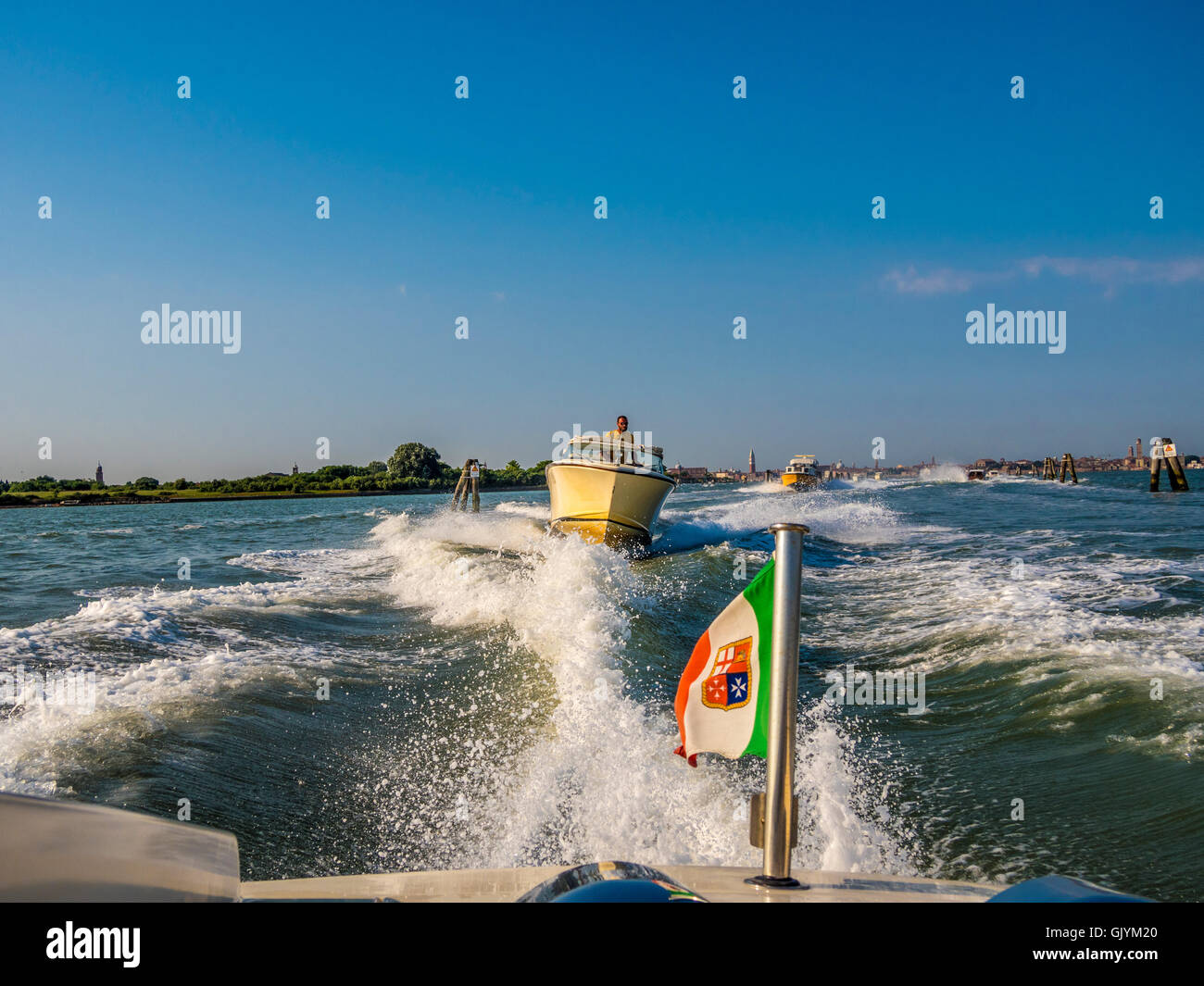 Italian Flag on the stern of a water taxi, travelling at speed. Venice, Italy. Stock Photo