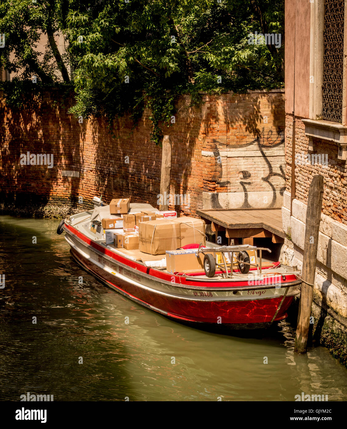 Delivery boat laden with parcels moored in a small canal in Venice, Italy. Stock Photo