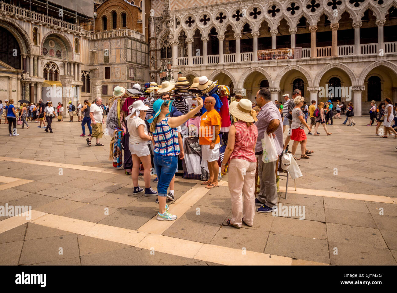 Female tourist taking selfie, having tried on a sun hat from a stall in the Piazetta San Marco in Venice, Italy. Stock Photo