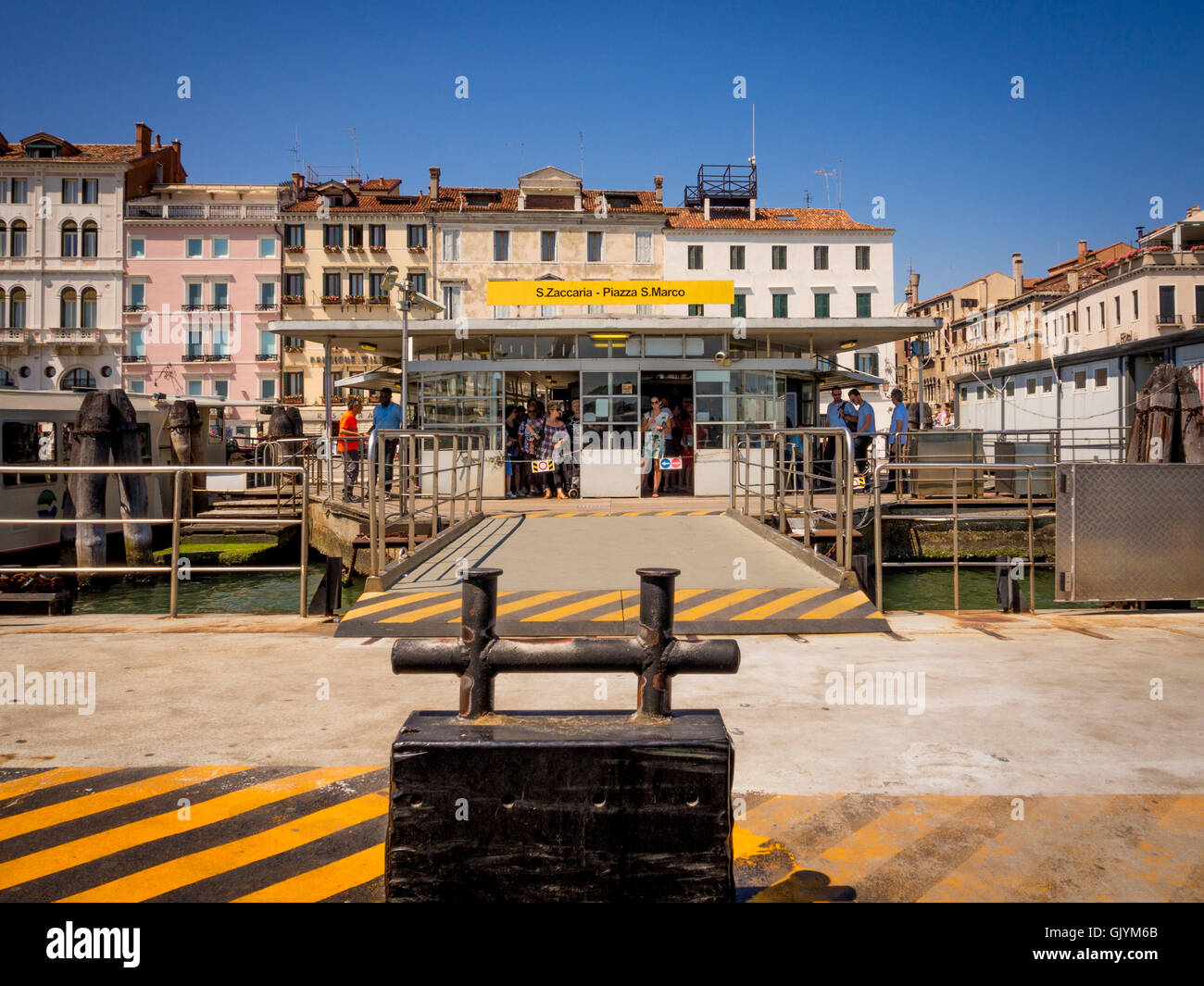 Bollard to secure a stationary vaporetto to with the terminal in the background. Venice, Italy. Stock Photo