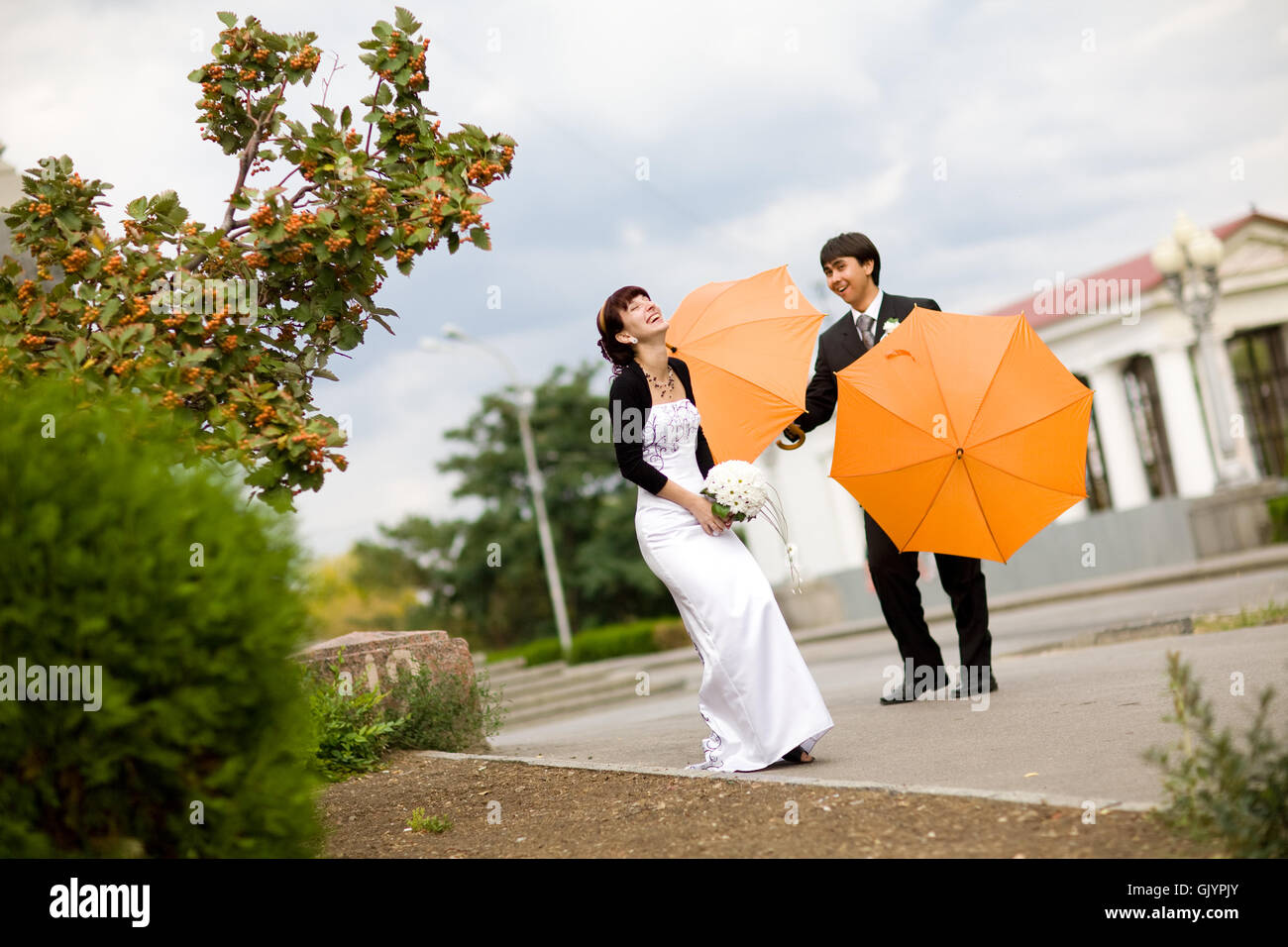 bride and groom with orange umbrellas Stock Photo