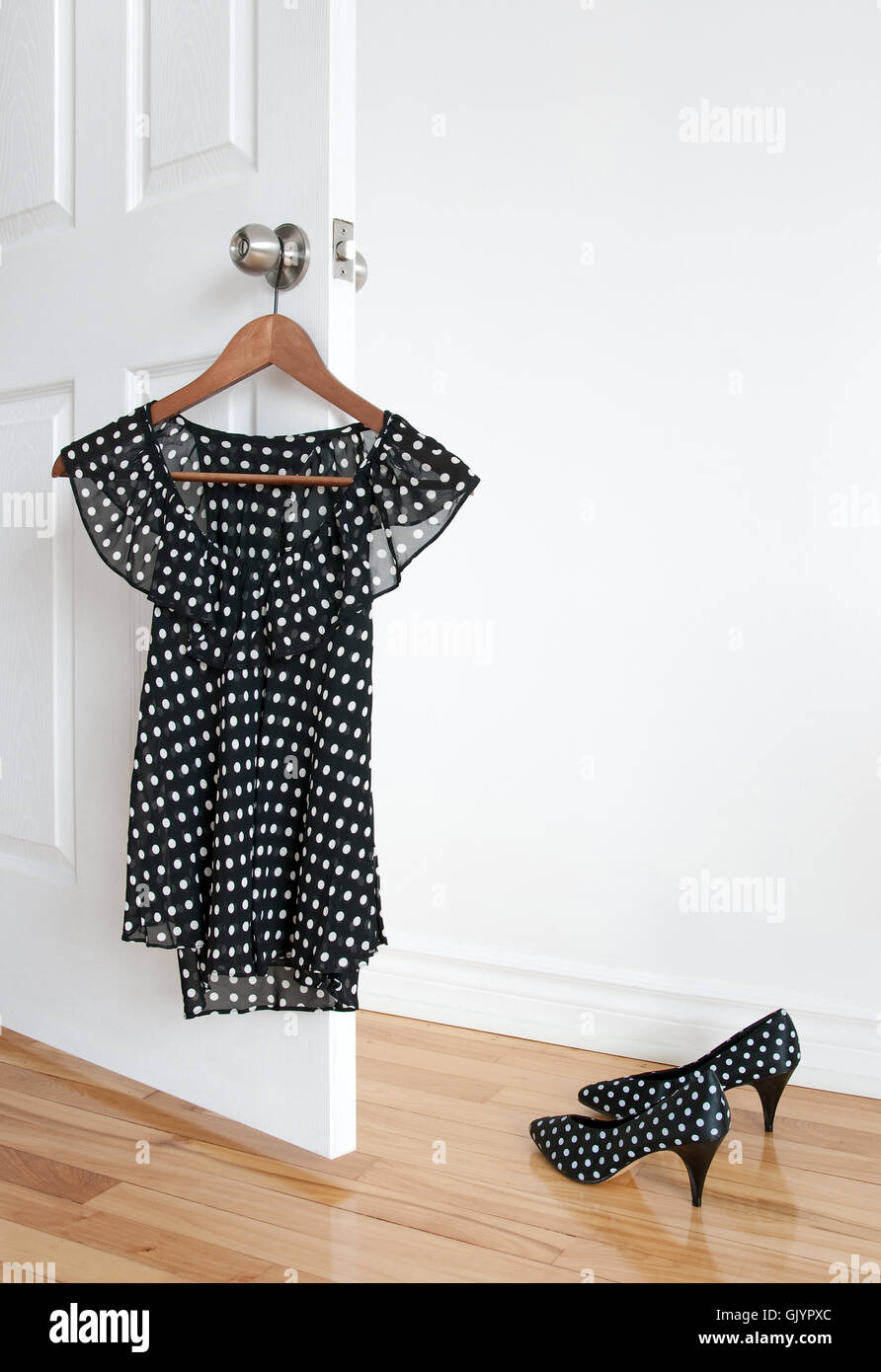 Polka dot blouse on a hanger and shoes on the floor Stock Photo