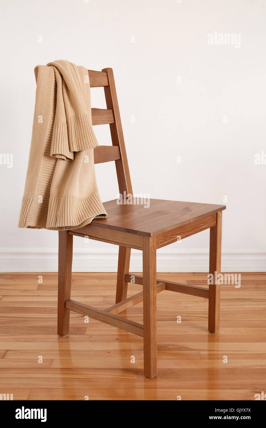 Chair on wooden floor with clothing put over its back Stock Photo