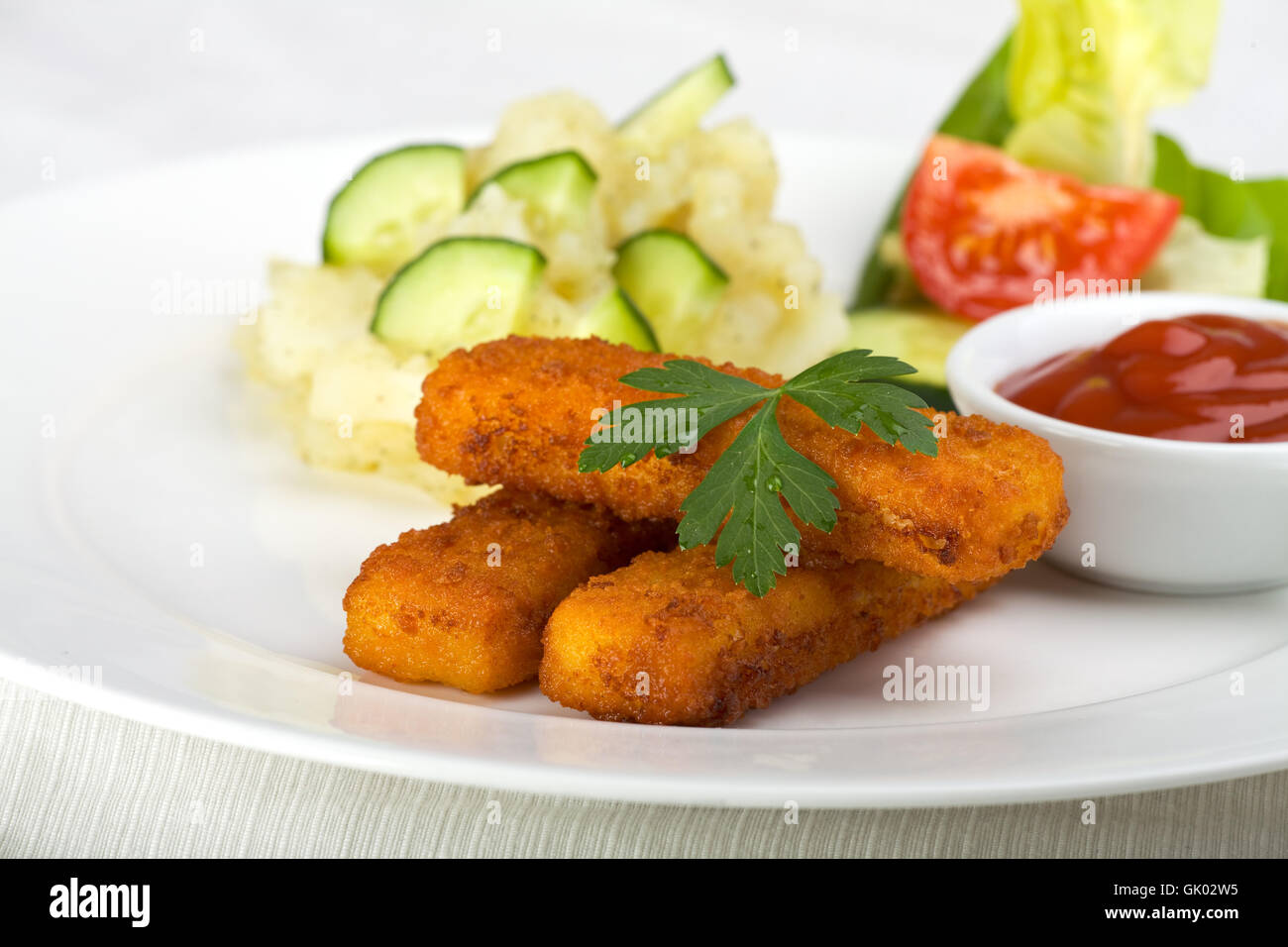 three fish fingers and potato salad Stock Photo