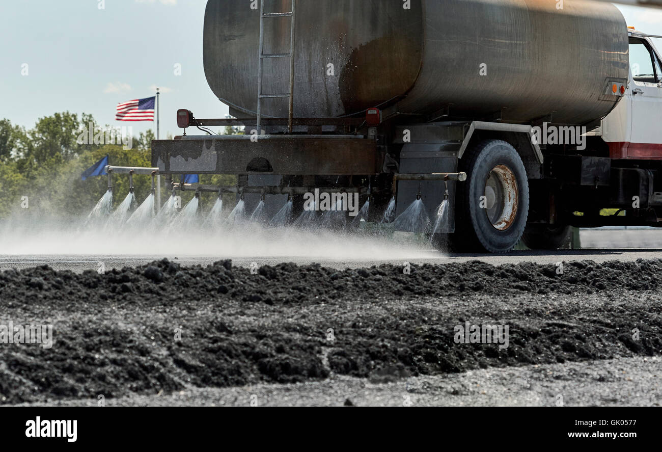 Water truck spraying water on roadway in preparation for construction