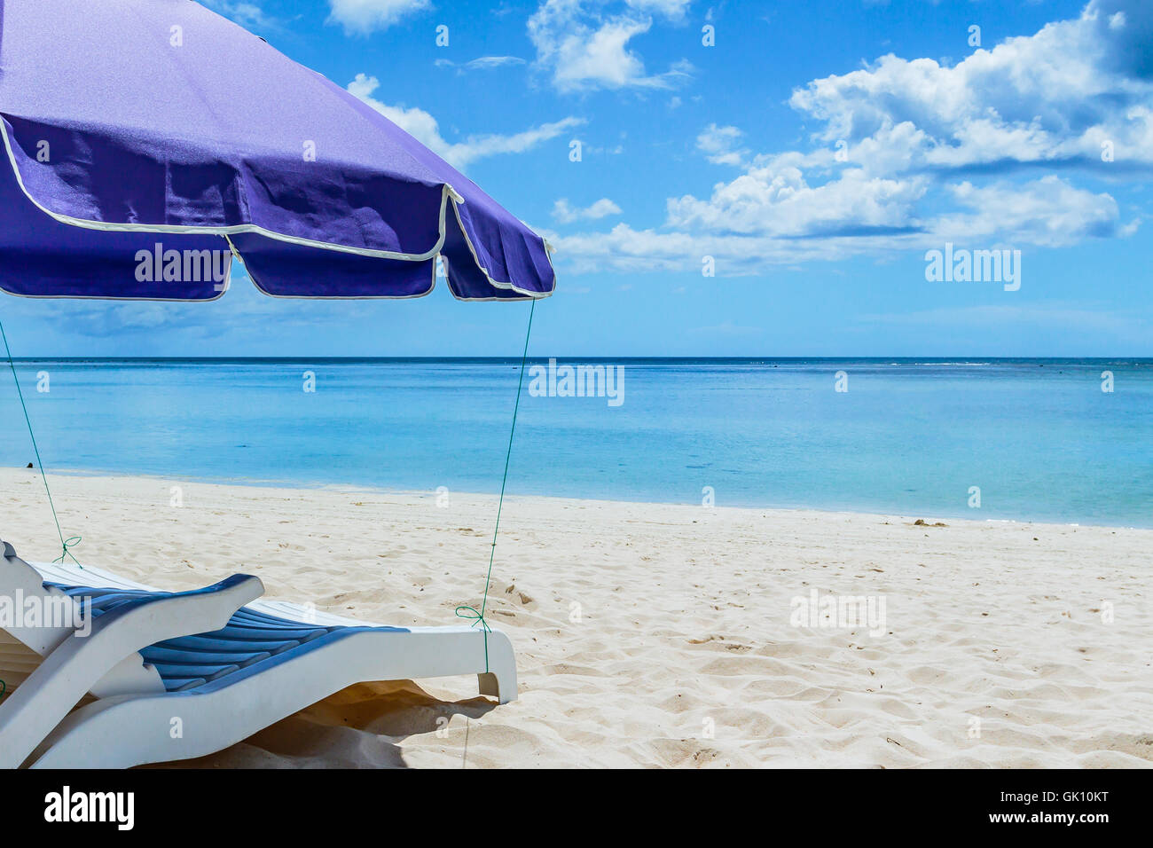A pair of beach chairs under an umbrella on a deserted beach with white sand Stock Photo Alamy