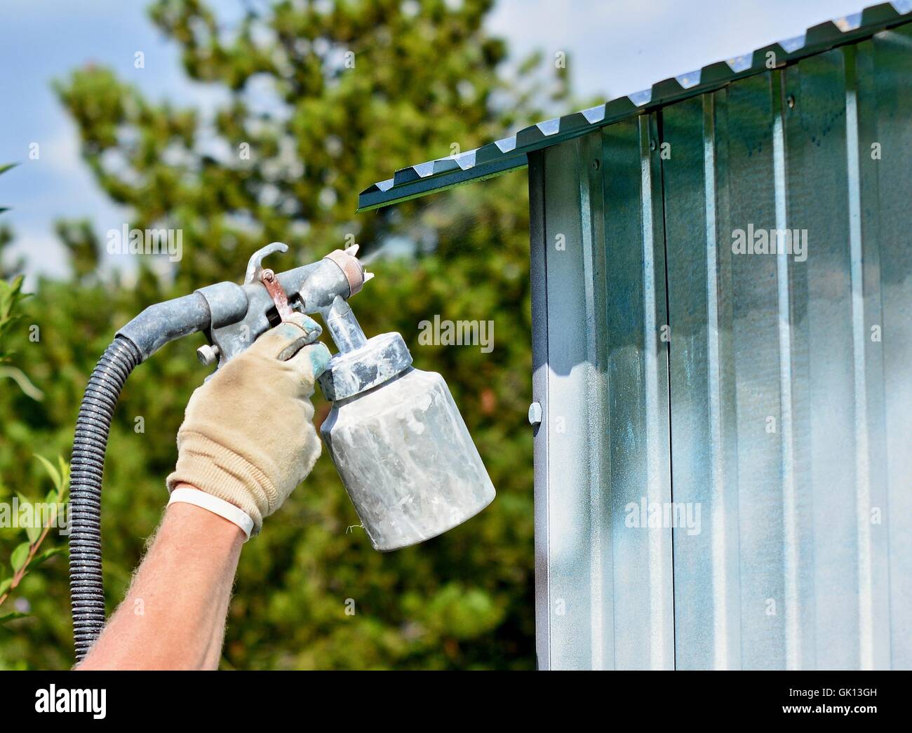 Spraying white paint onto a galvanized surface by an airbrush gun Stock