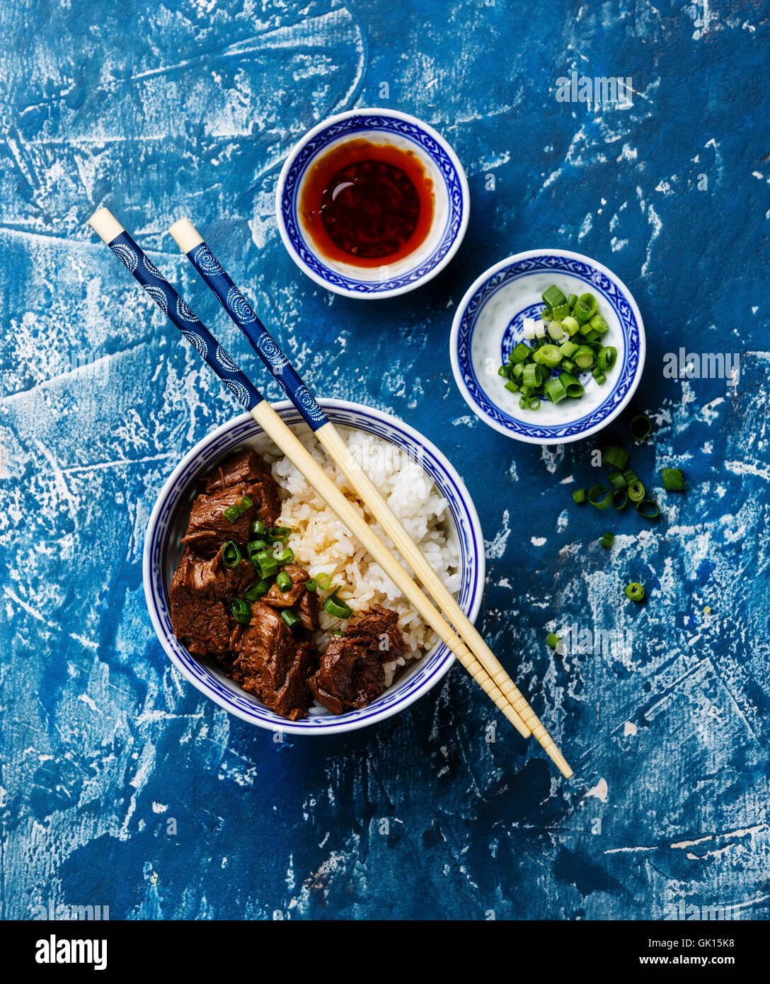 Slow cooked Beef with Rice and green onions in bowl on blue background Stock Photo