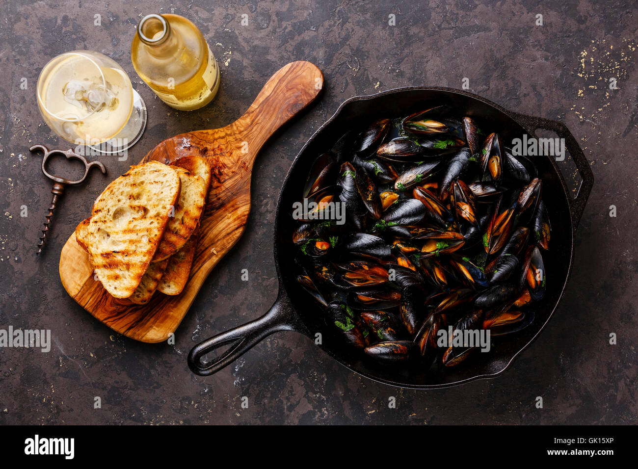 Mussels on frying pan, Bread toasts and Wine on dark background Stock Photo