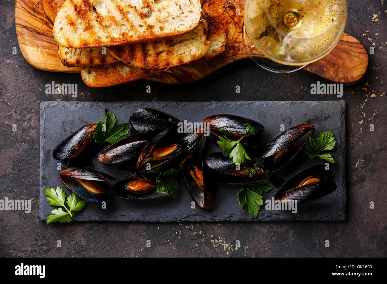 Mussels on stone slate, Bread toasts and Wine on dark background Stock Photo
