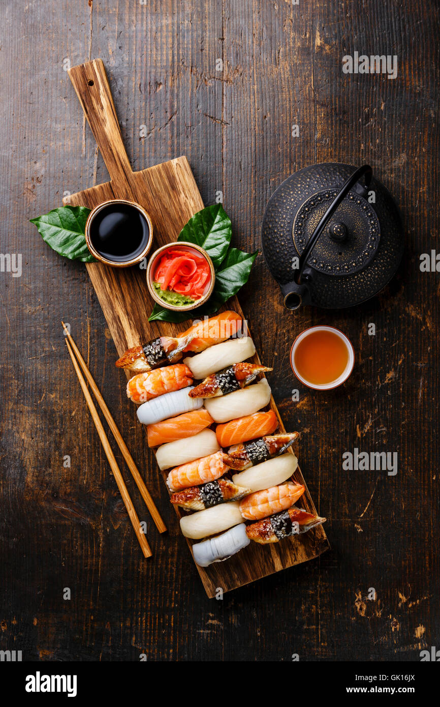 Nigiri Sushi set on wooden serving board and green tea on dark wooden background Stock Photo