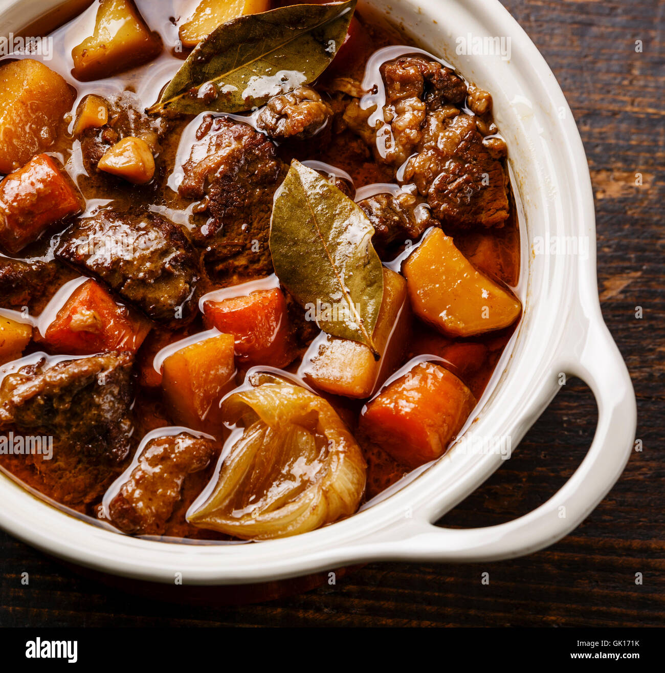 Beef meat stewed with potatoes, carrots and spices in ceramic pot close up Stock Photo
