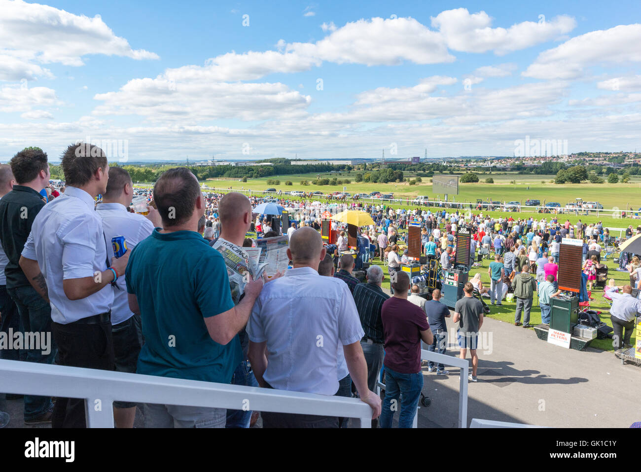 A day at the races. Friends enjoy a beer while watching the horse ...